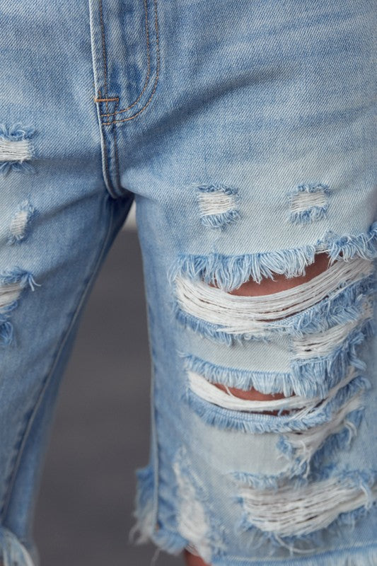 Close-up of ripped high-rise bermuda denim shorts, frayed distressed patch detail