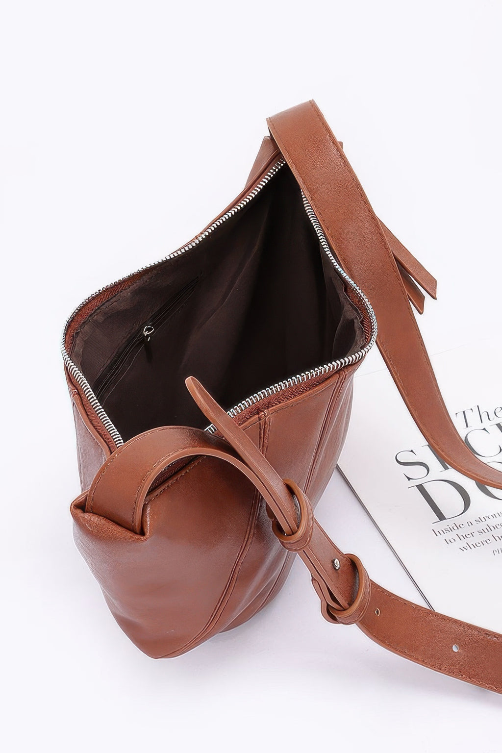 Faux leather croissant bag open, showing dark lining and zip-top closure