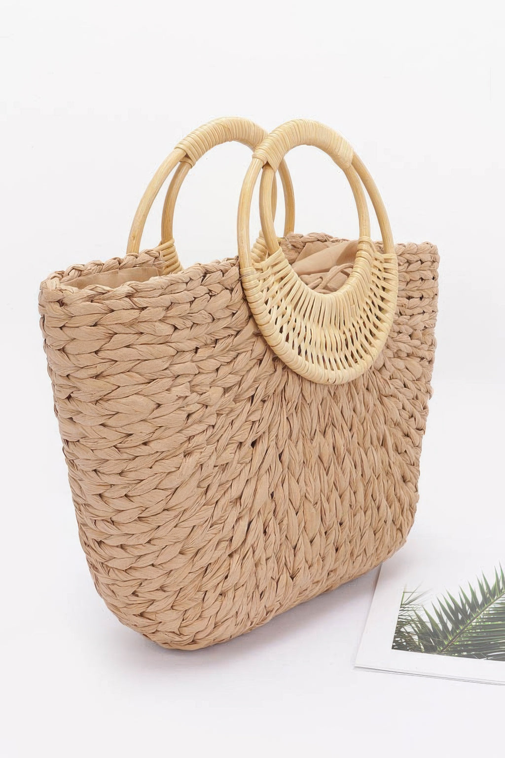 Khaki woven tote bag with bamboo-style double handles, textured straw front