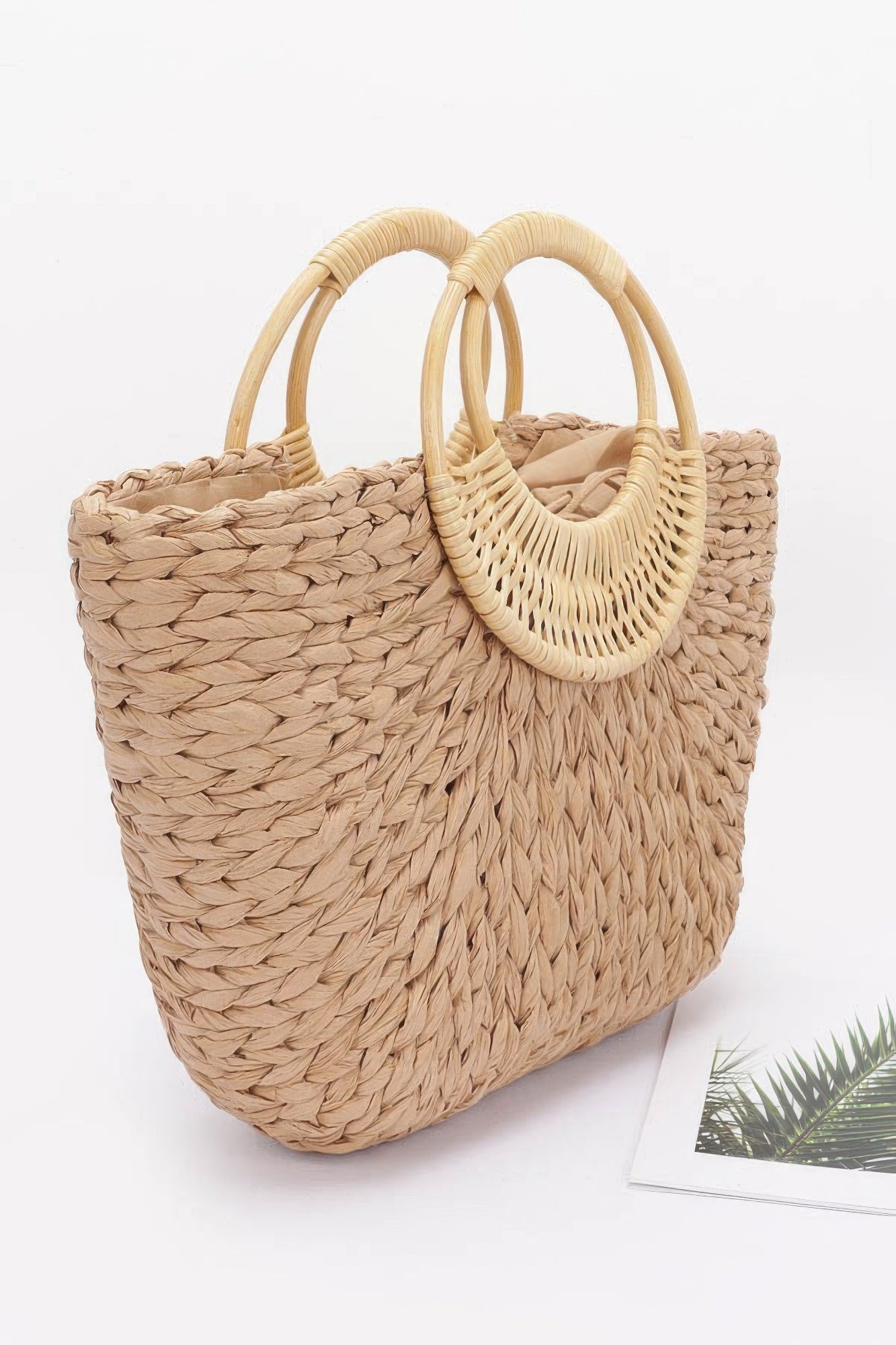 Khaki woven tote bag with bamboo-style double handles, textured straw front