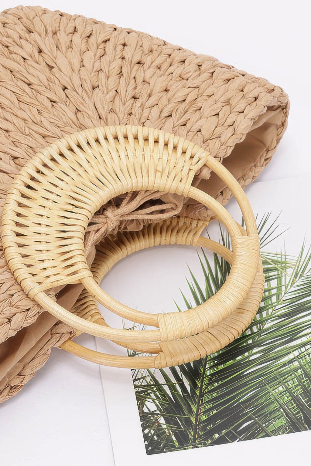 Khaki woven straw tote close-up with bamboo handle rings and woven texture