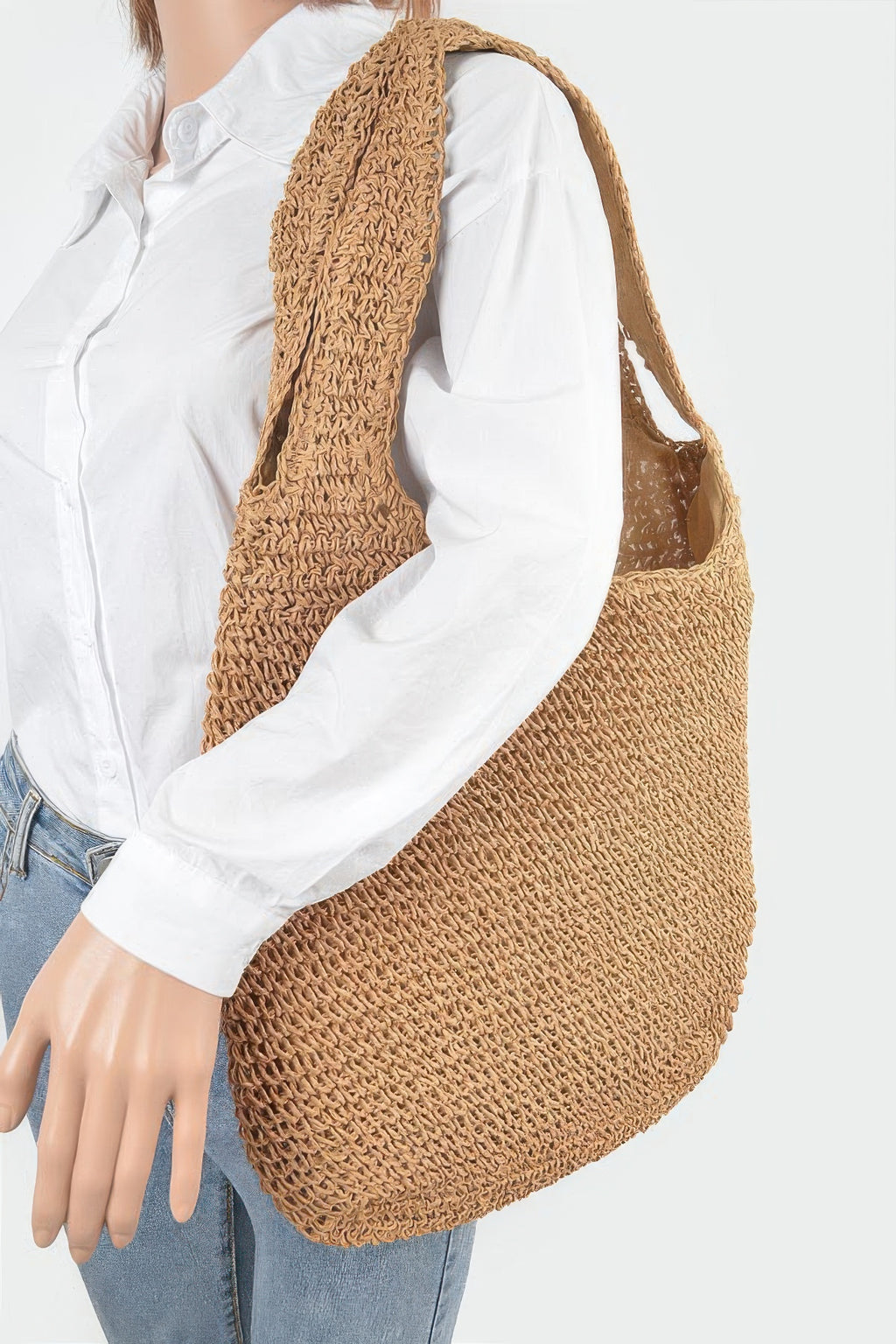 Faux straw hobo bag worn over a white shirt; tan woven texture, short handles
