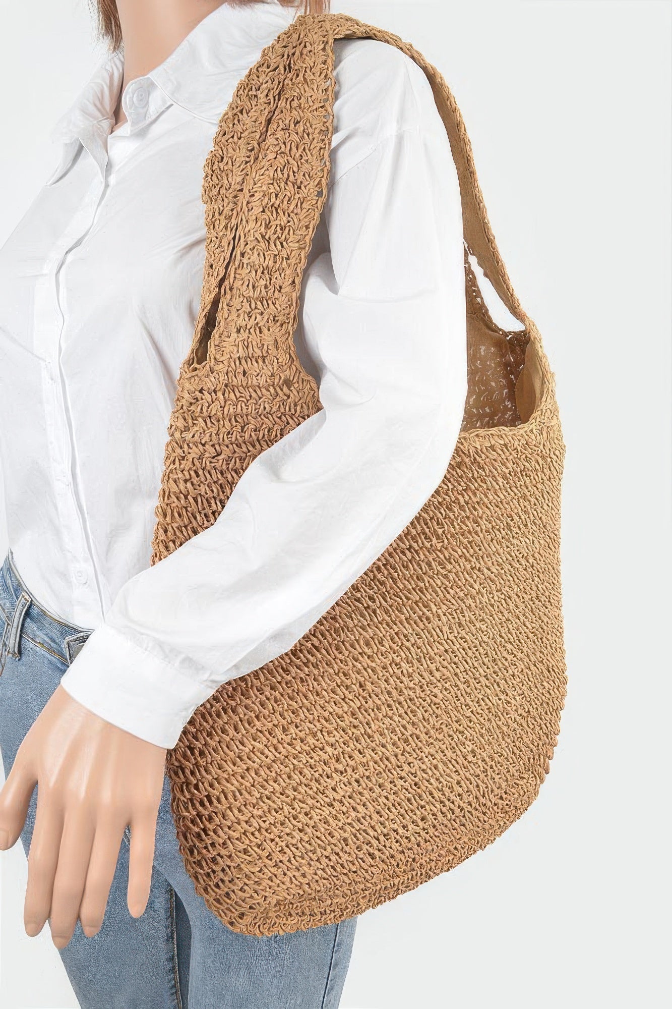 Faux straw hobo bag worn over a white shirt; tan woven texture, short handles