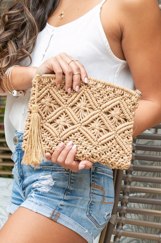 Khaki macrame tassel clutch with woven diamond motif, held in hands