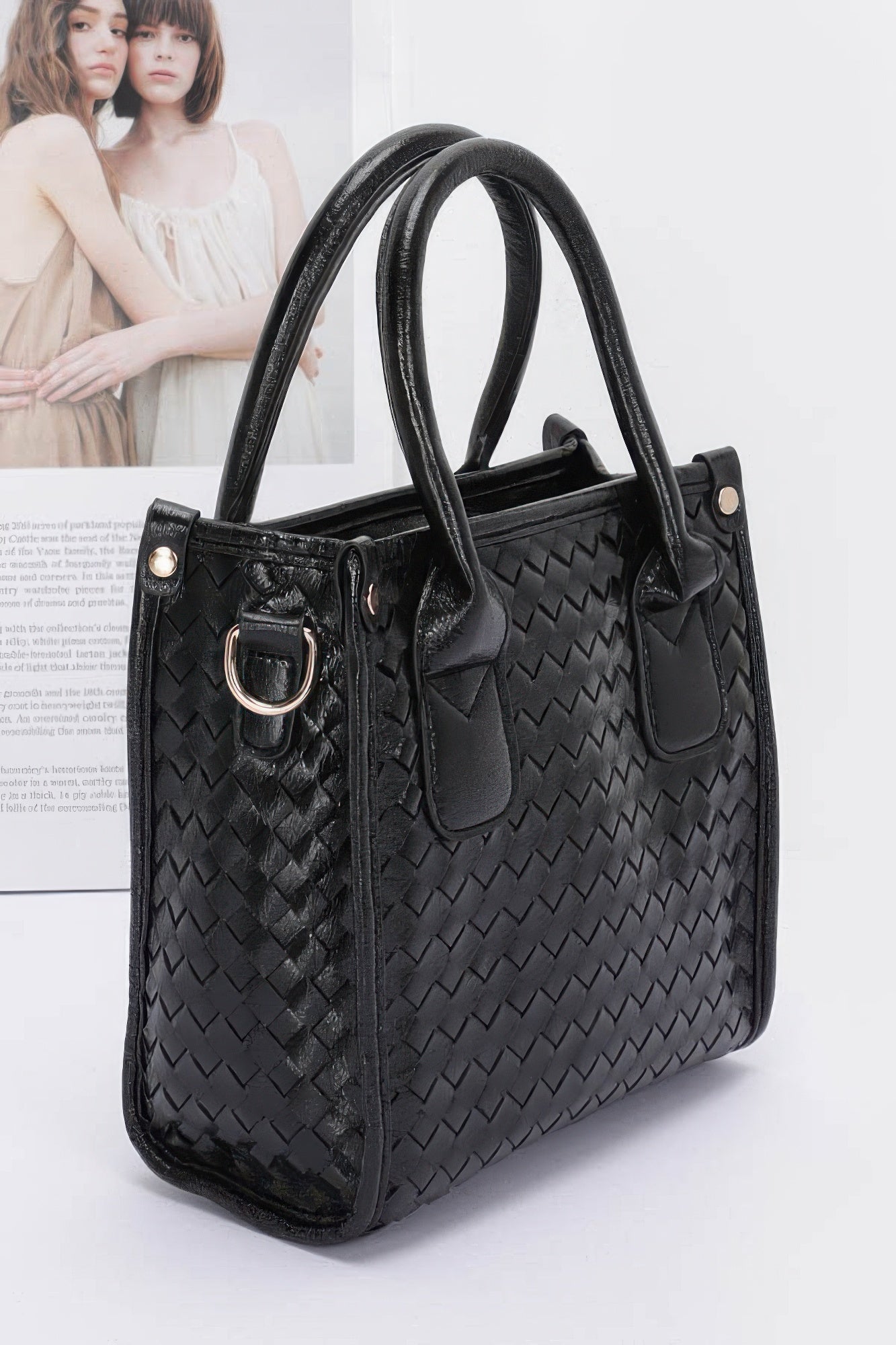 Black metallic braided tote bag with dual handles, shoulder strap, and front clasp ring