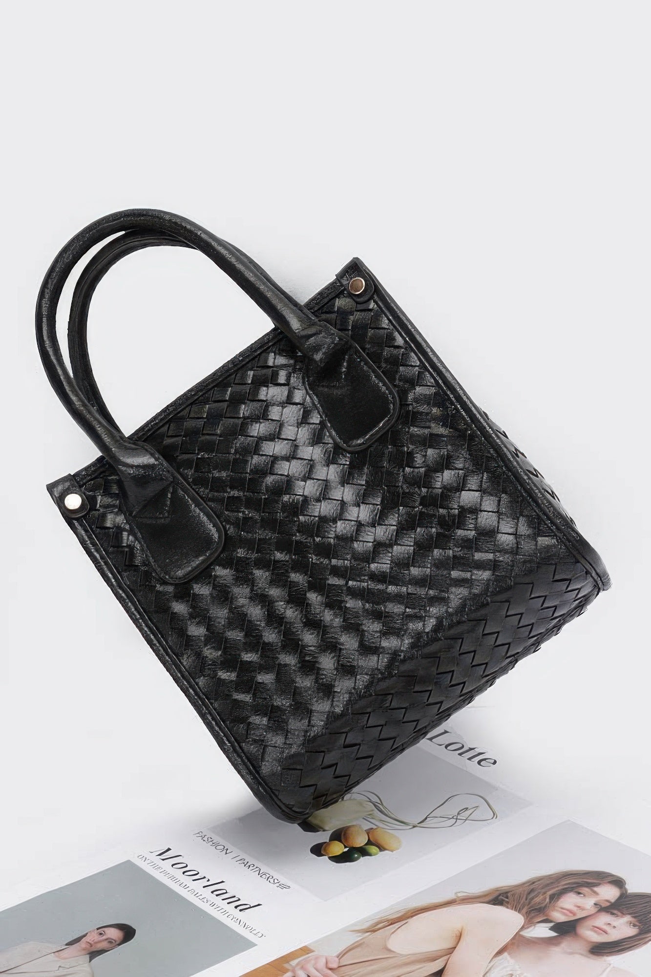 Black metallic braided tote bag angled view with woven diamond texture and dual pockets