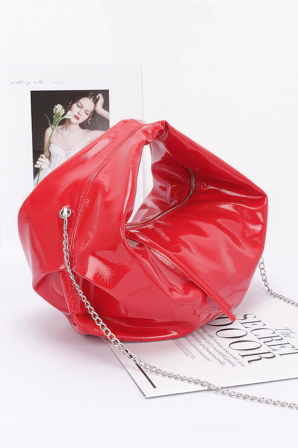 Red patent leather hobo bag with chain shoulder strap and tassel detail