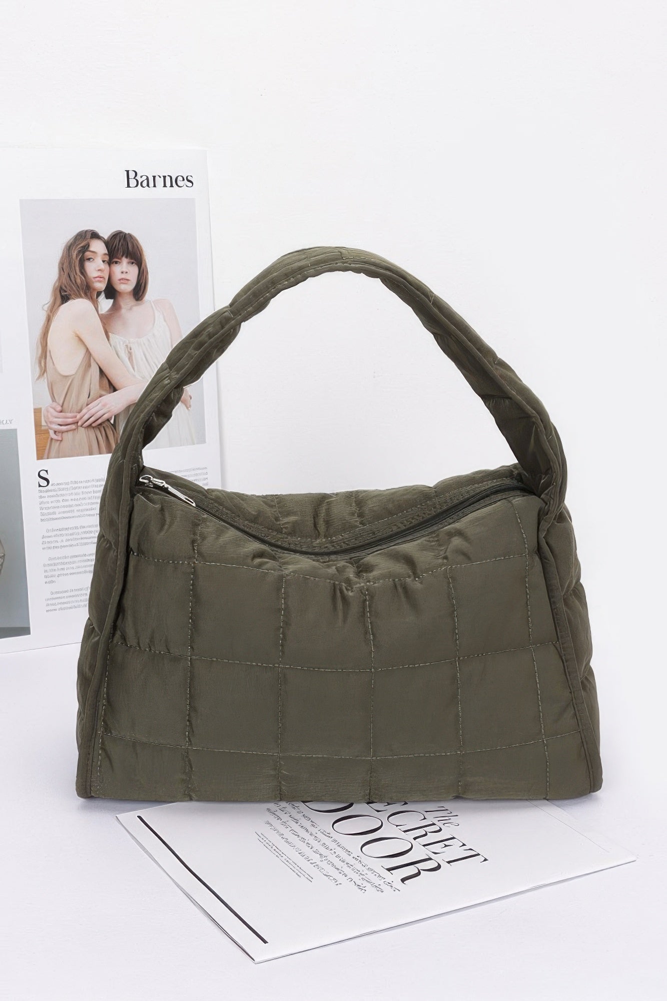 Quilted nylon shoulder bag in olive green with curved top handle and stitched panels