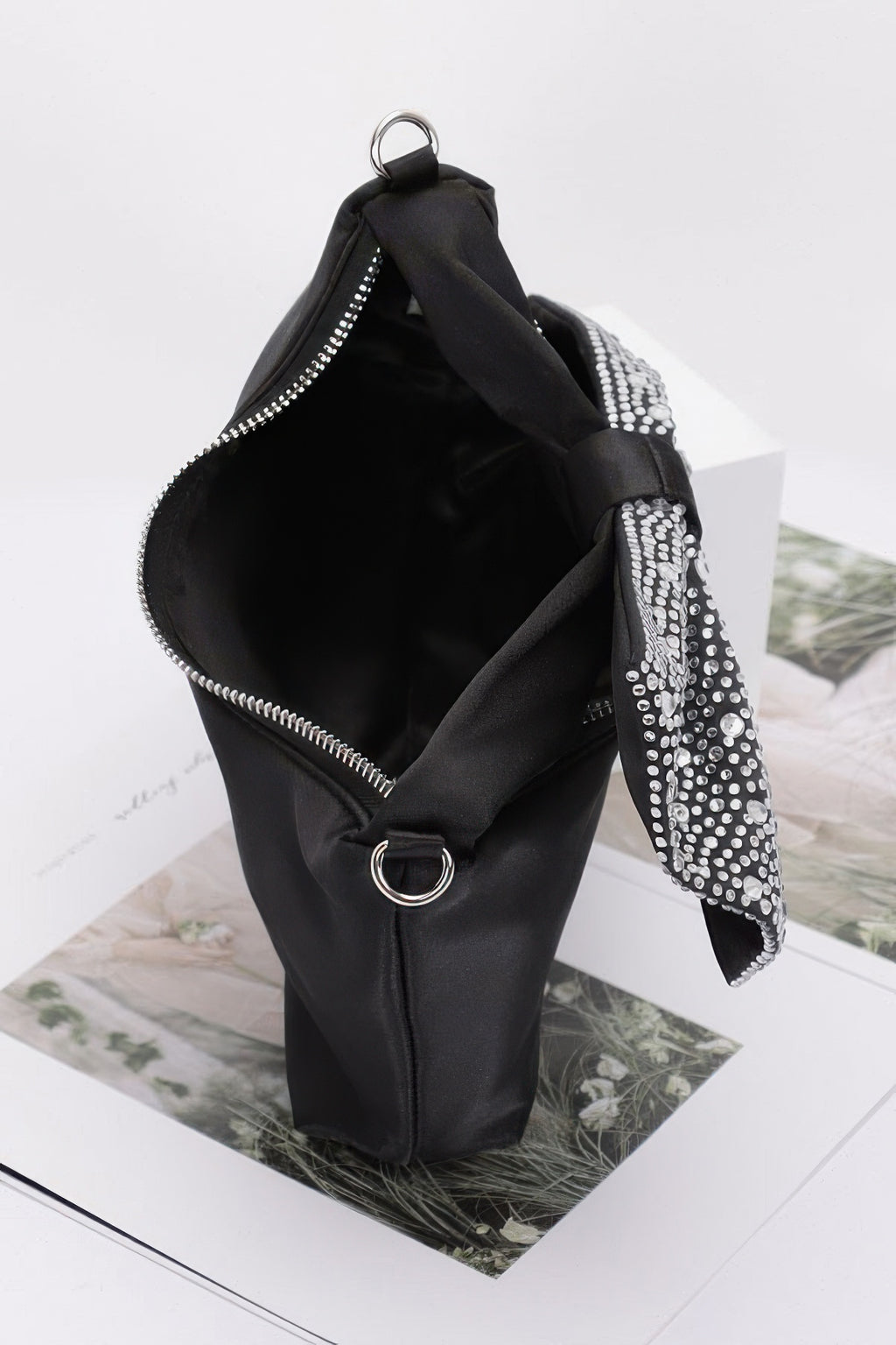 Black nylon clutch open with zip and rhinestone bow handle detail