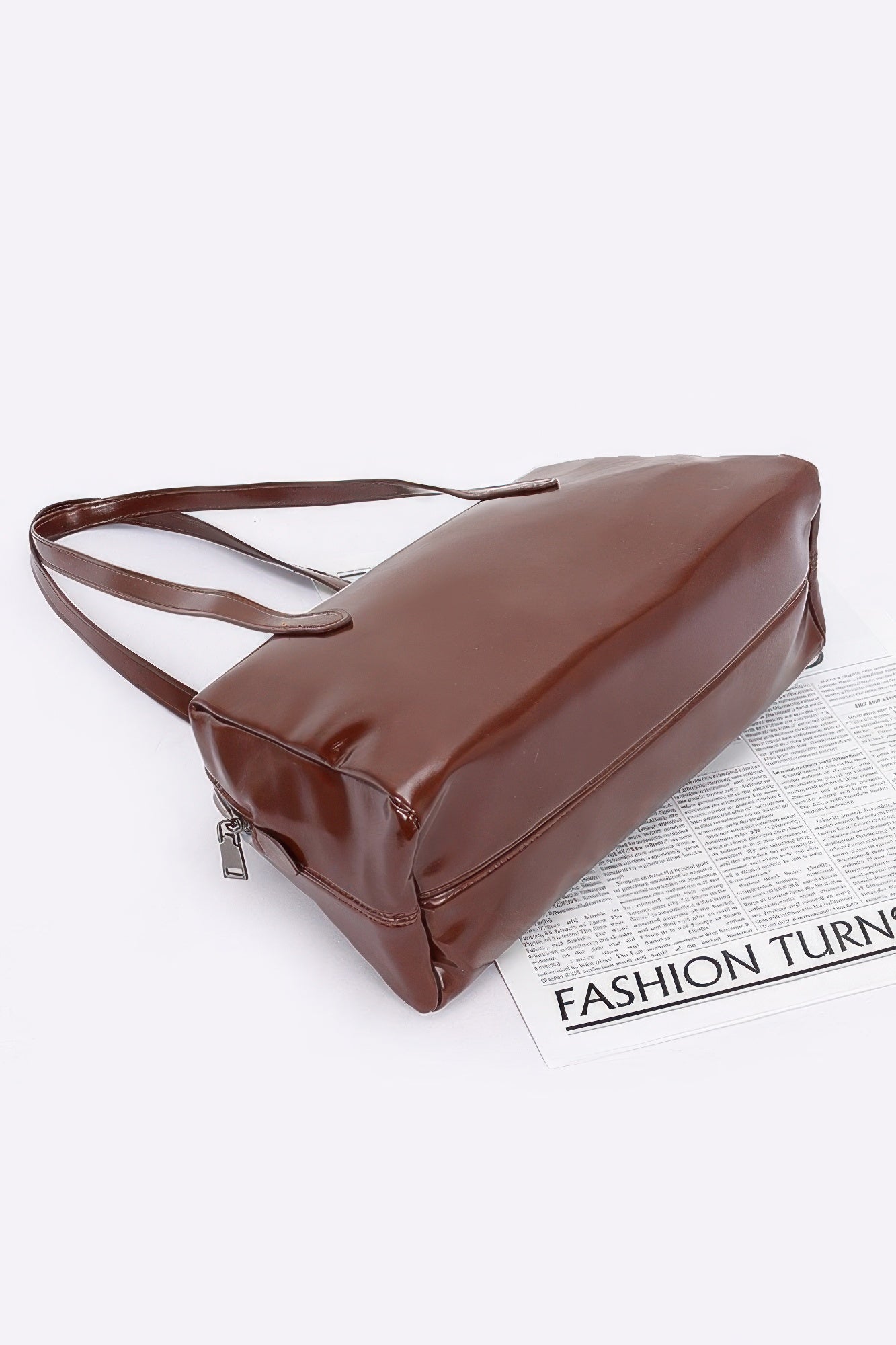 Shiny faux leather sport handbag in brown, angled view with shoulder strap