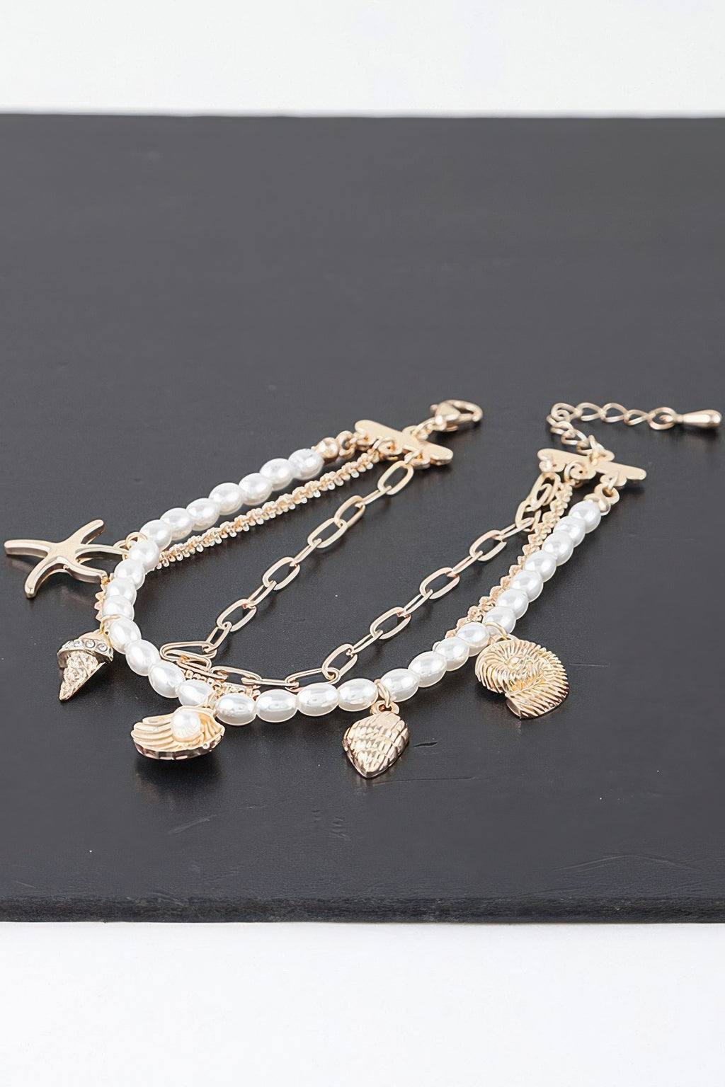 Multi charm bracelet with gold-tone chain, pearl beads, starfish and shell charms