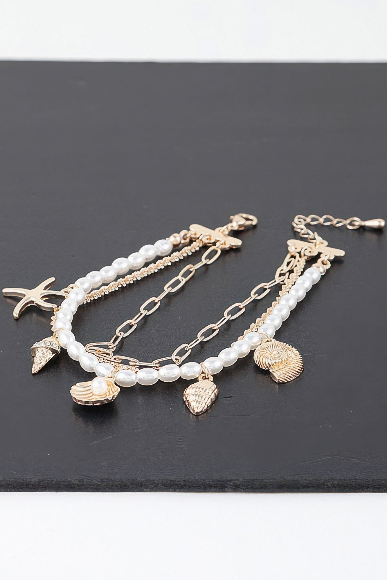 Multi charm bracelet with gold-tone chain, pearl beads, starfish and shell charms