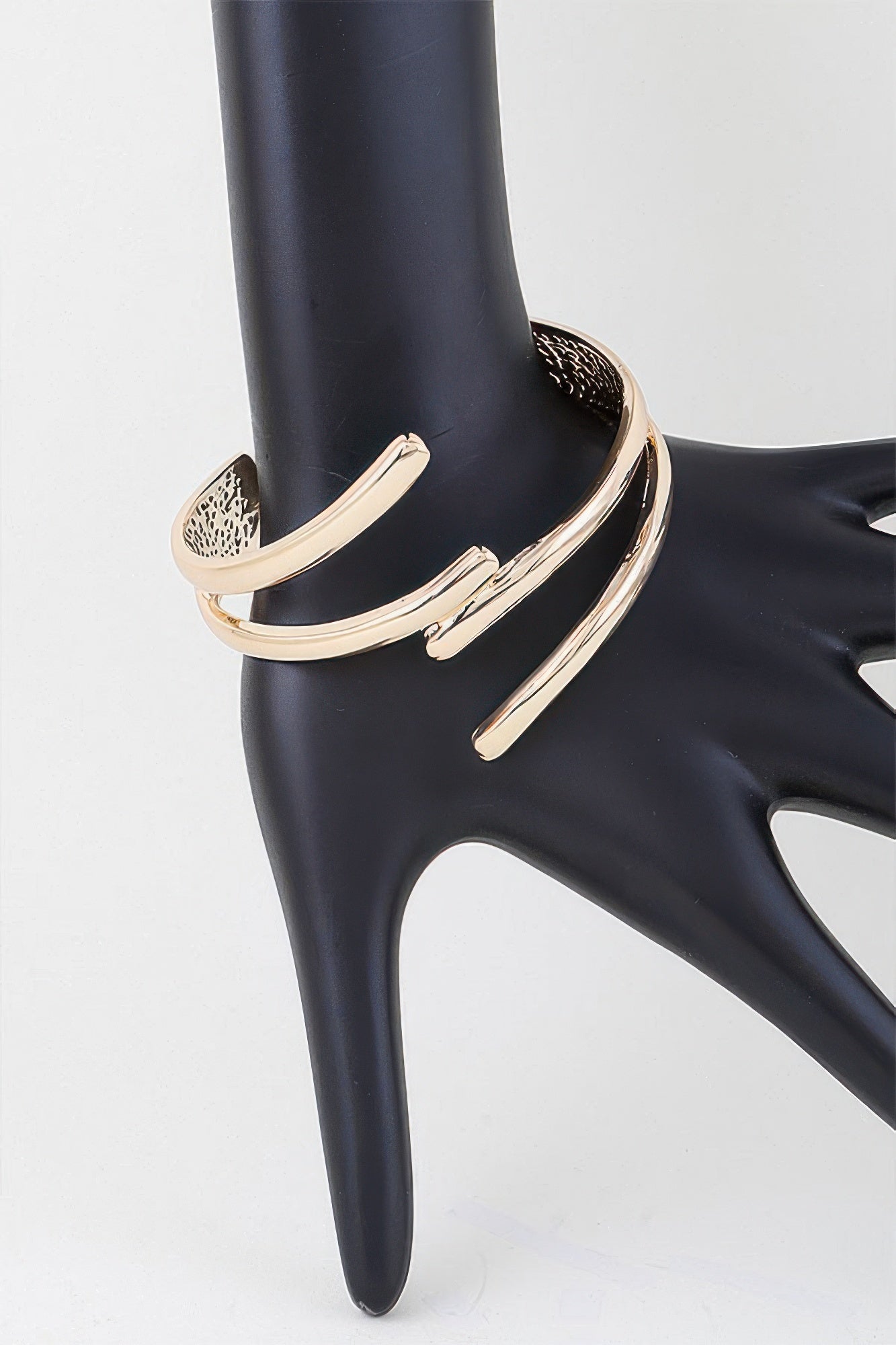 Delicate gold cuff bracelet with three open bar segments, worn on wrist form