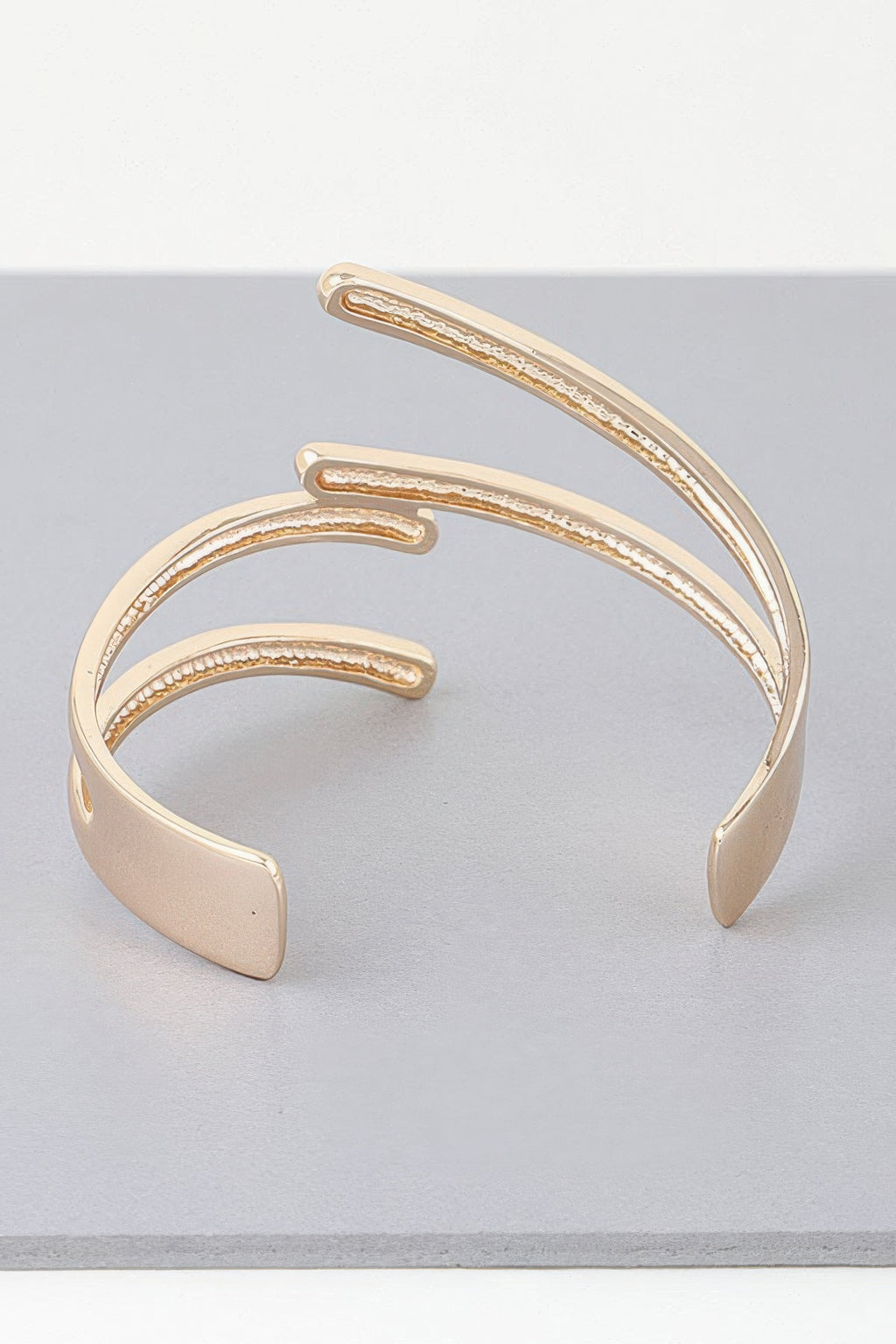 Wide gold open cuff bracelet with double-layer curved bars and smooth outer edges