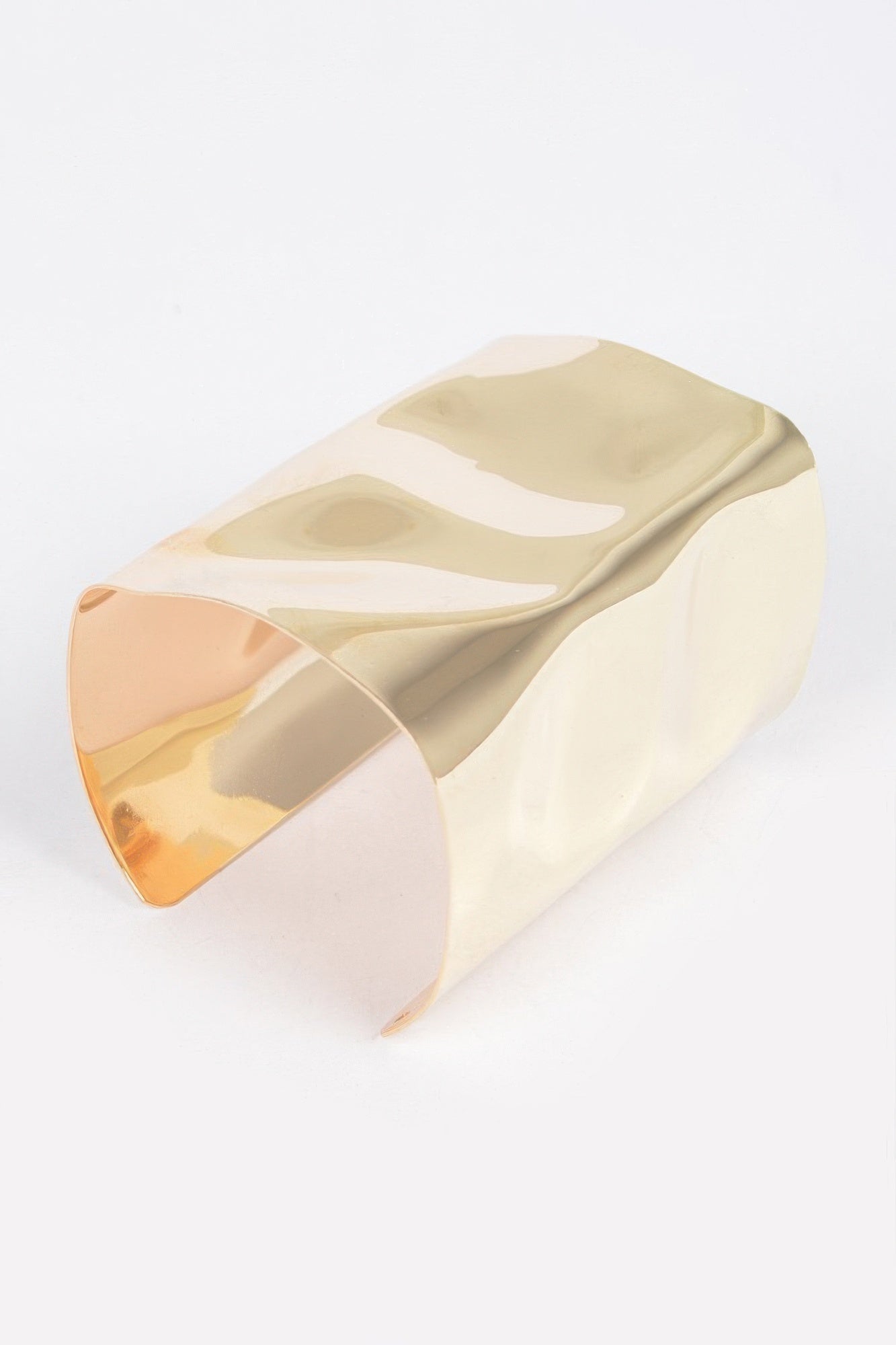 Gold-tone metal cuff bracelet shown from side, open back with smooth reflective surface