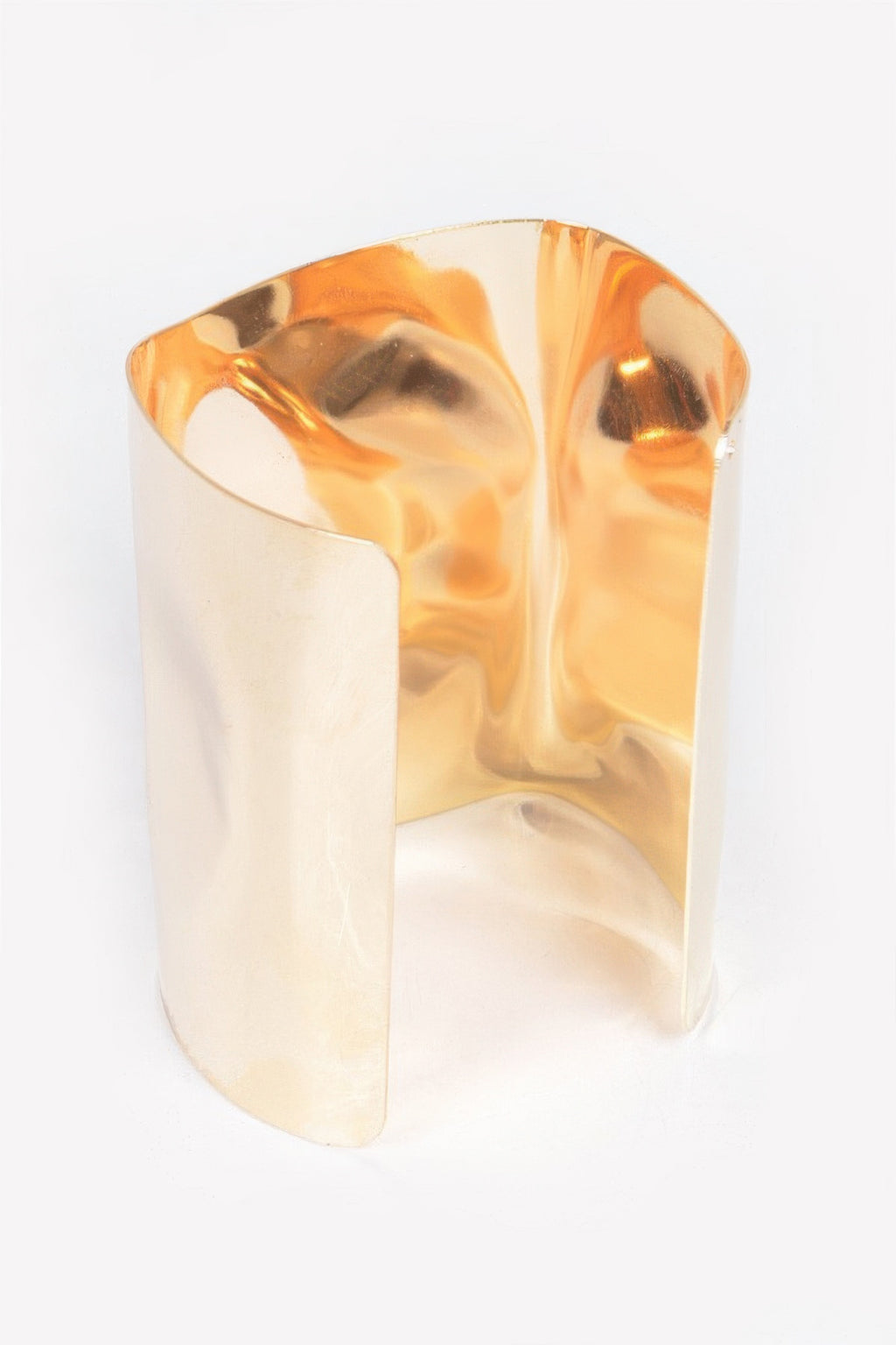 Gold-tone metal cuff bracelet, close side view with reflective hammered-like highlights