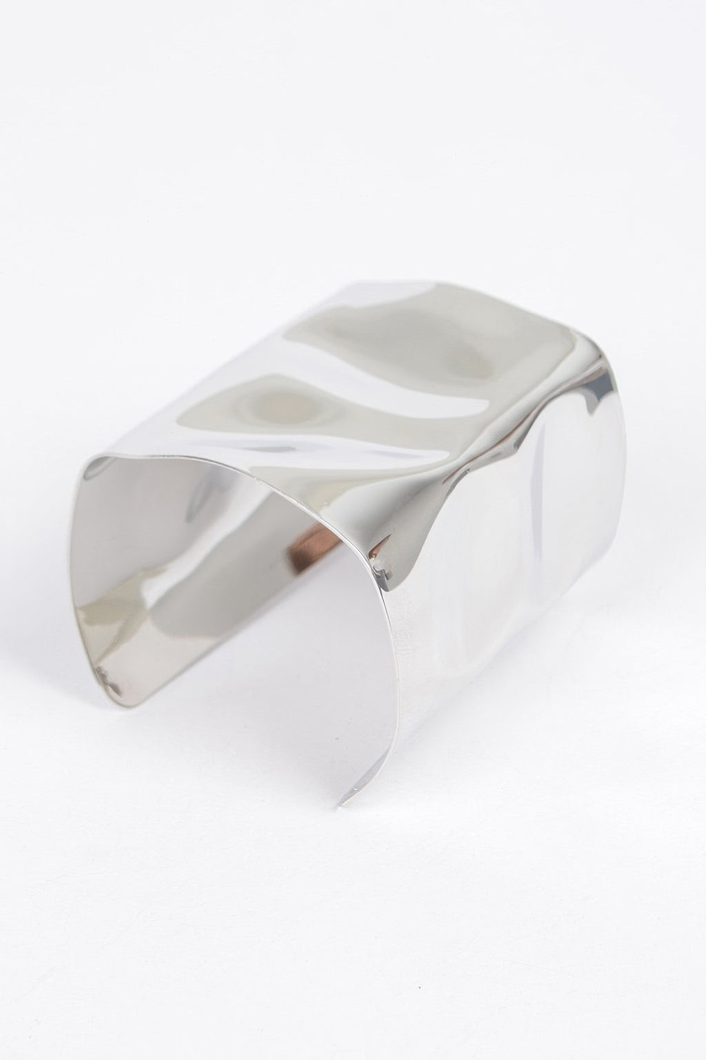 Silver-tone metal cuff bracelet from angled view, glossy curved metal band