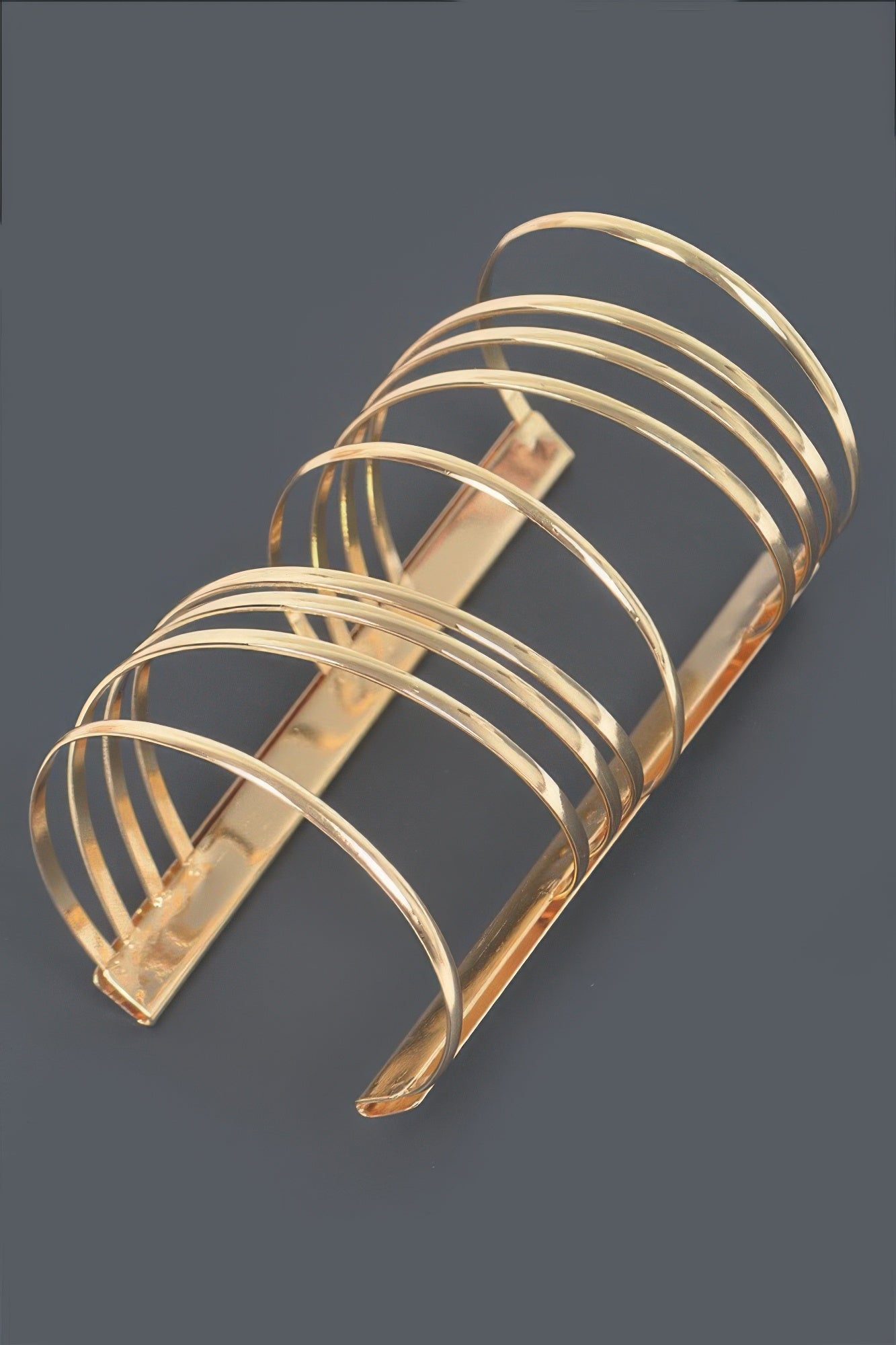 Gold metal cuff bracelet with stacked curved bands and central bar detail