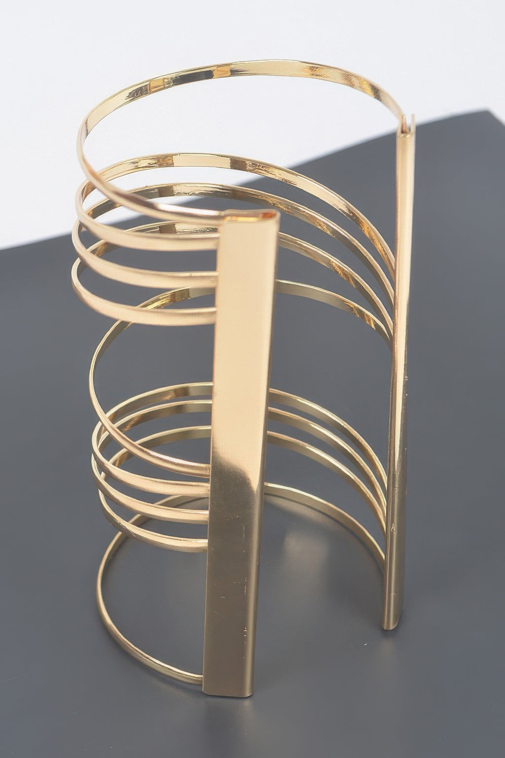 Gold metal cuff bracelet with tall vertical bar and layered open rings