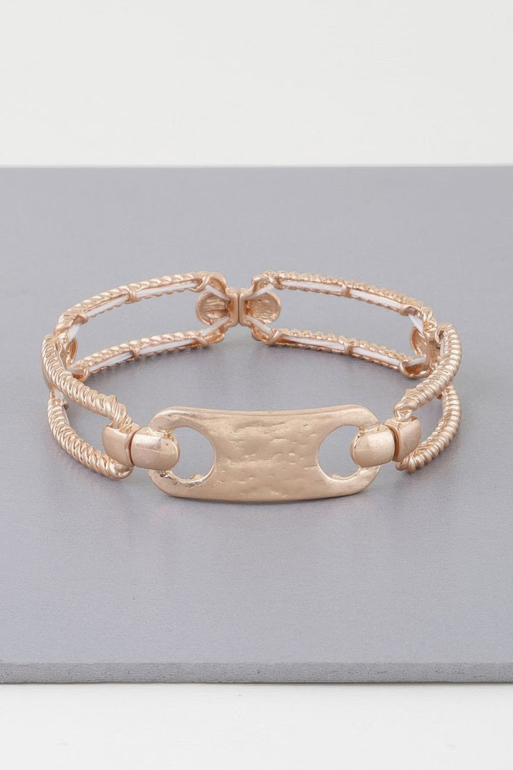 Gold twisted plate cuff bracelet with oval plate, rope chain, and interlinked clasp