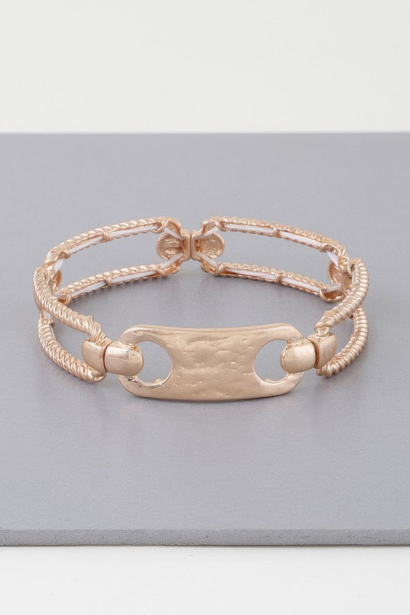Gold twisted plate cuff bracelet with oval plate, rope chain, and interlinked clasp