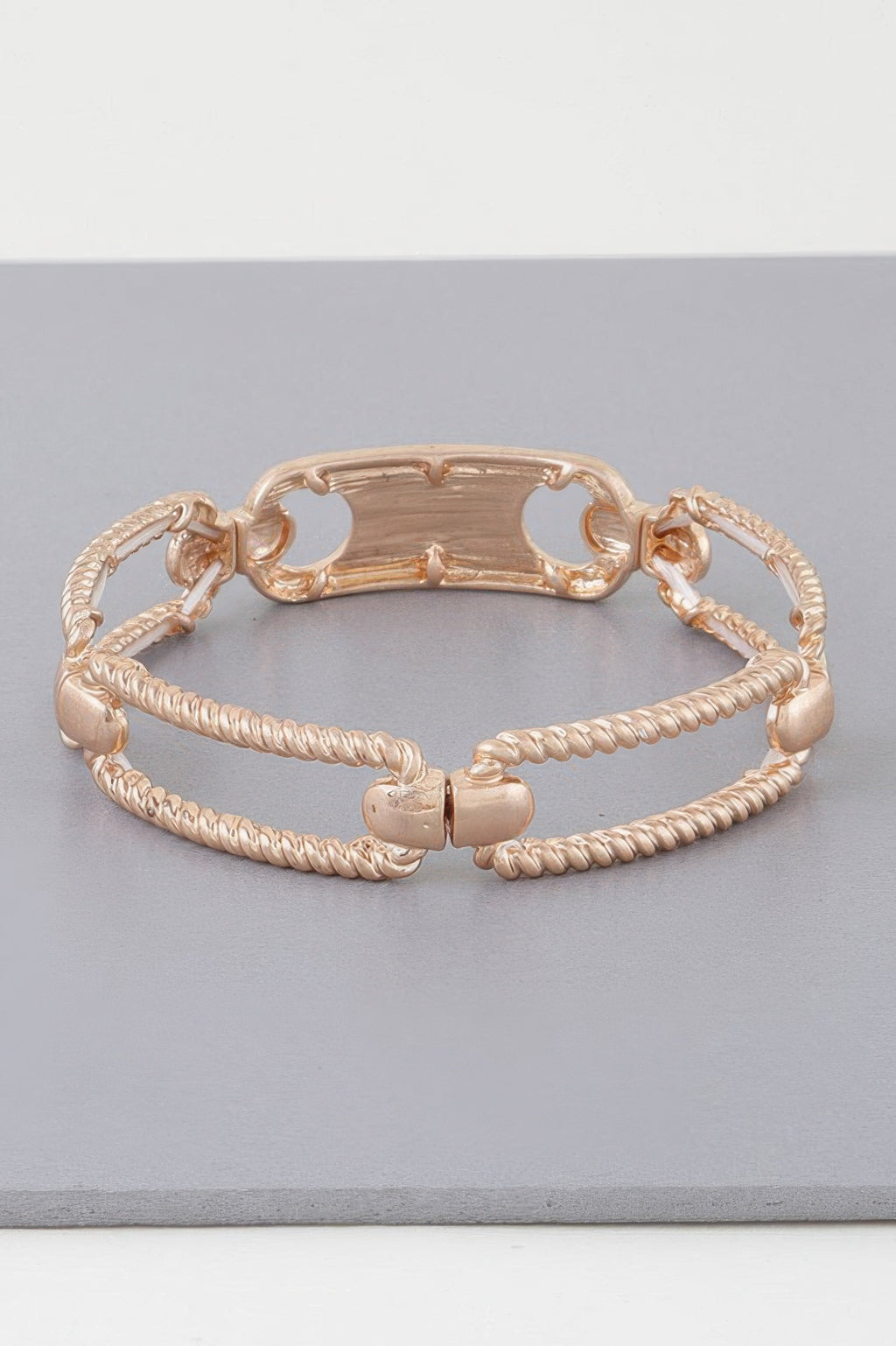 Gold twisted plate cuff bracelet with braided strands and openwork oval bar center