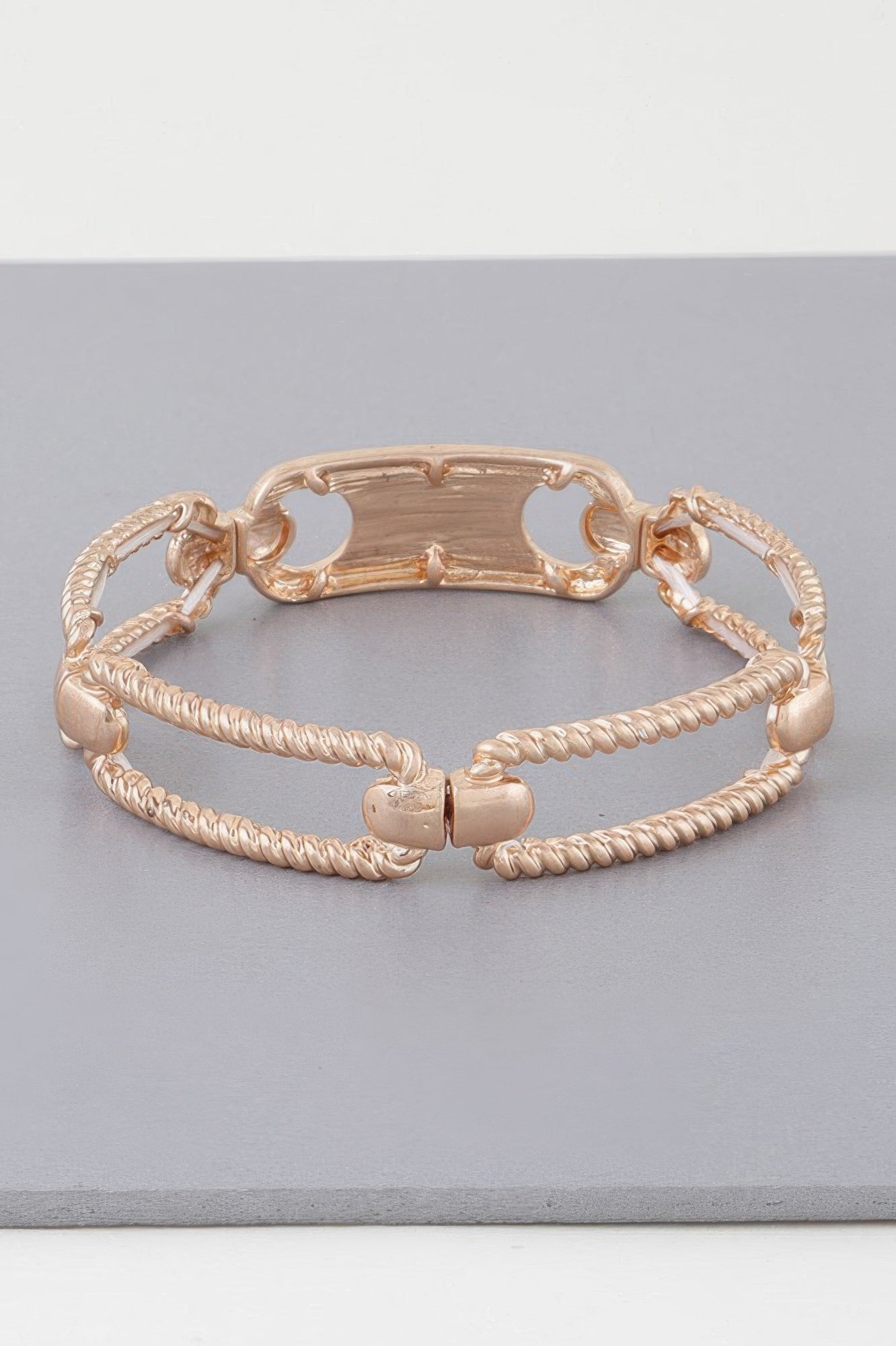 Gold twisted plate cuff bracelet with braided strands and openwork oval bar center