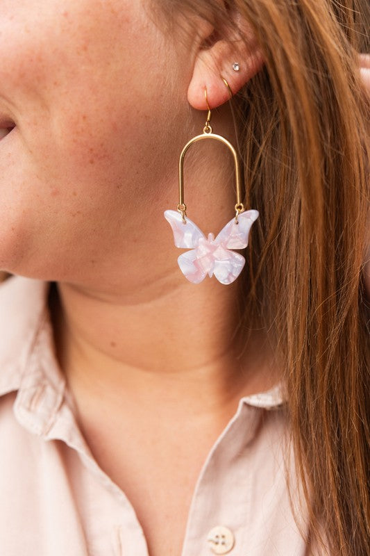 Enchanted butterfly earrings on model: gold hoop with pale pink butterfly charm