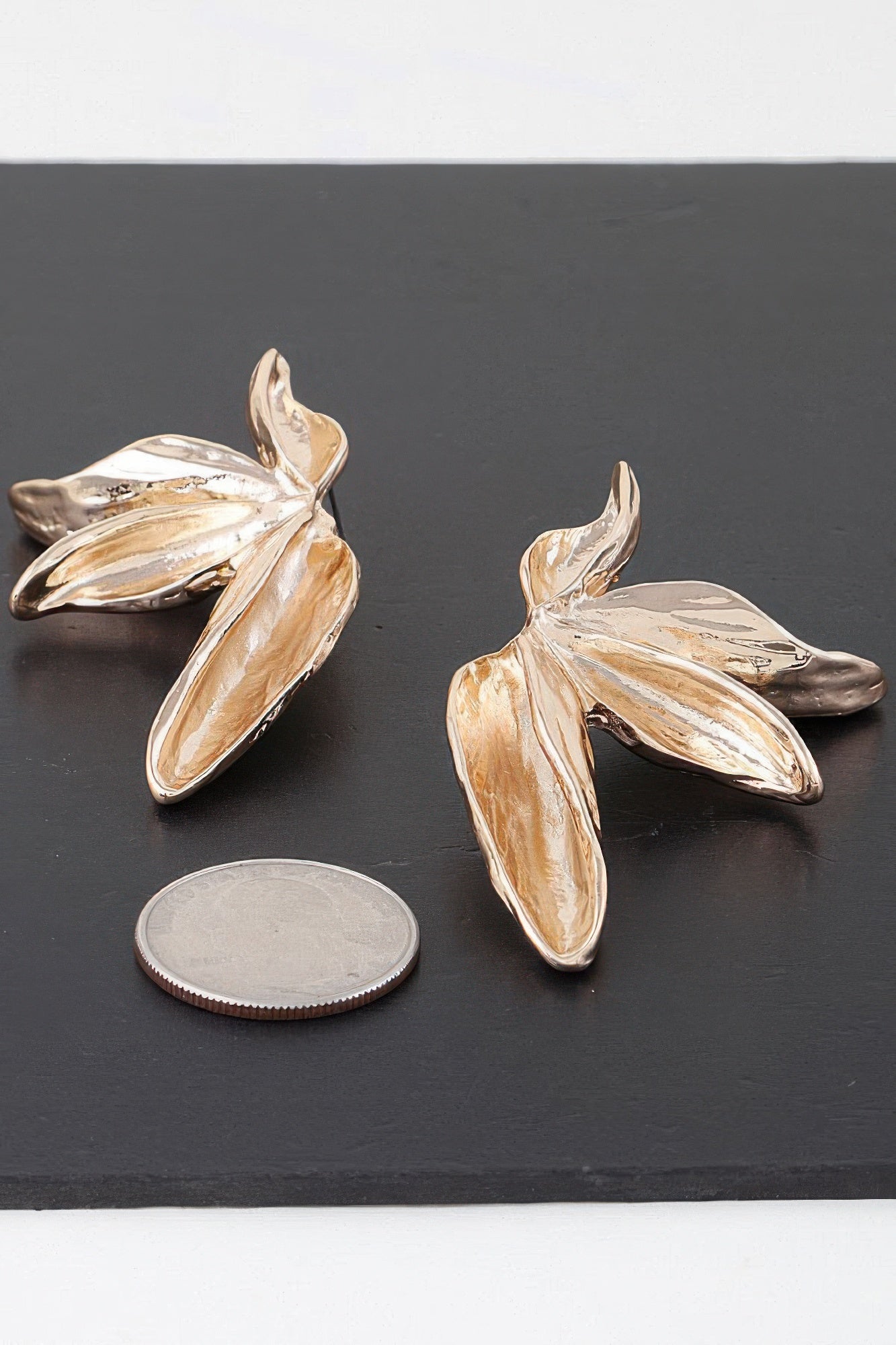 Gold flower-shaped earrings with layered petal design and reflective textured finish