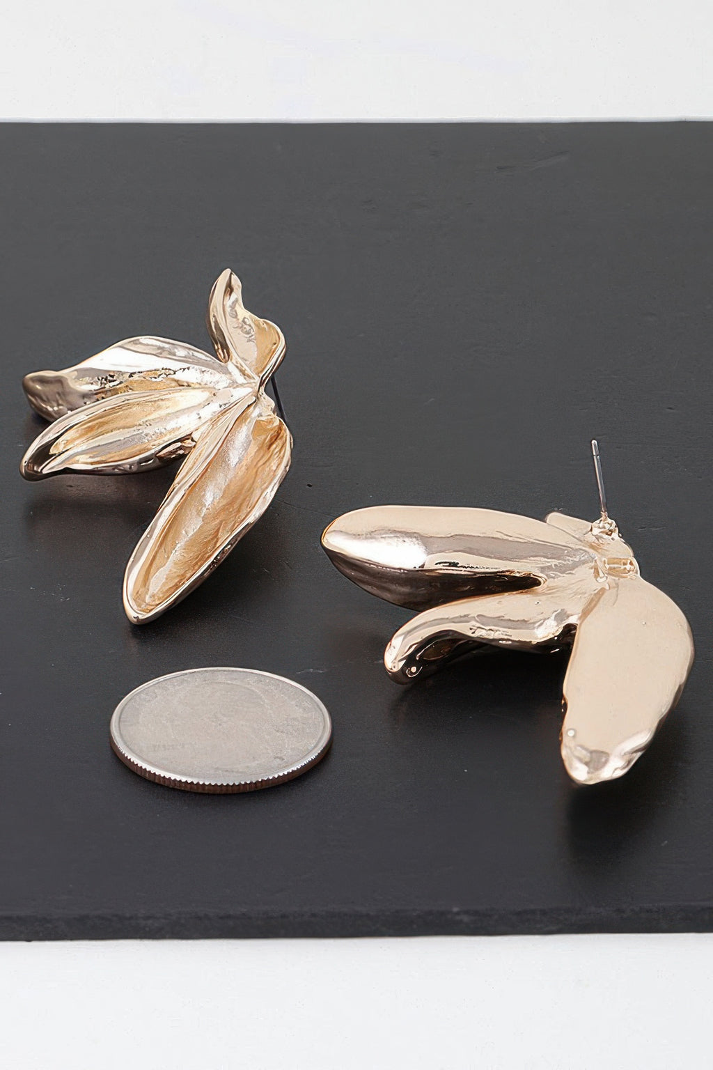 Gold bird-of-paradise earrings with visible stud post and curved petal shapes