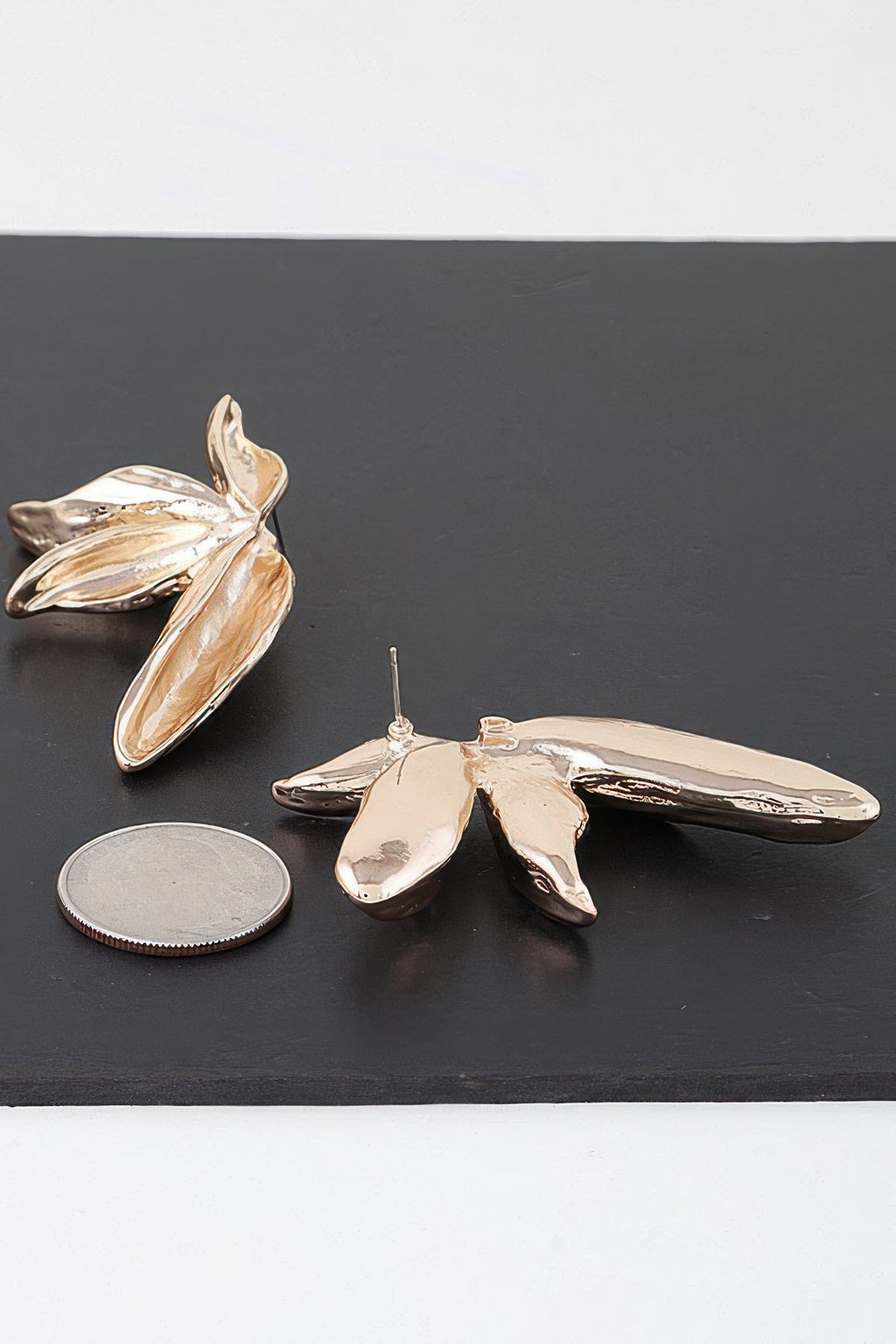 Gold flower earrings shown from the side, layered petals with smooth reflective sheen