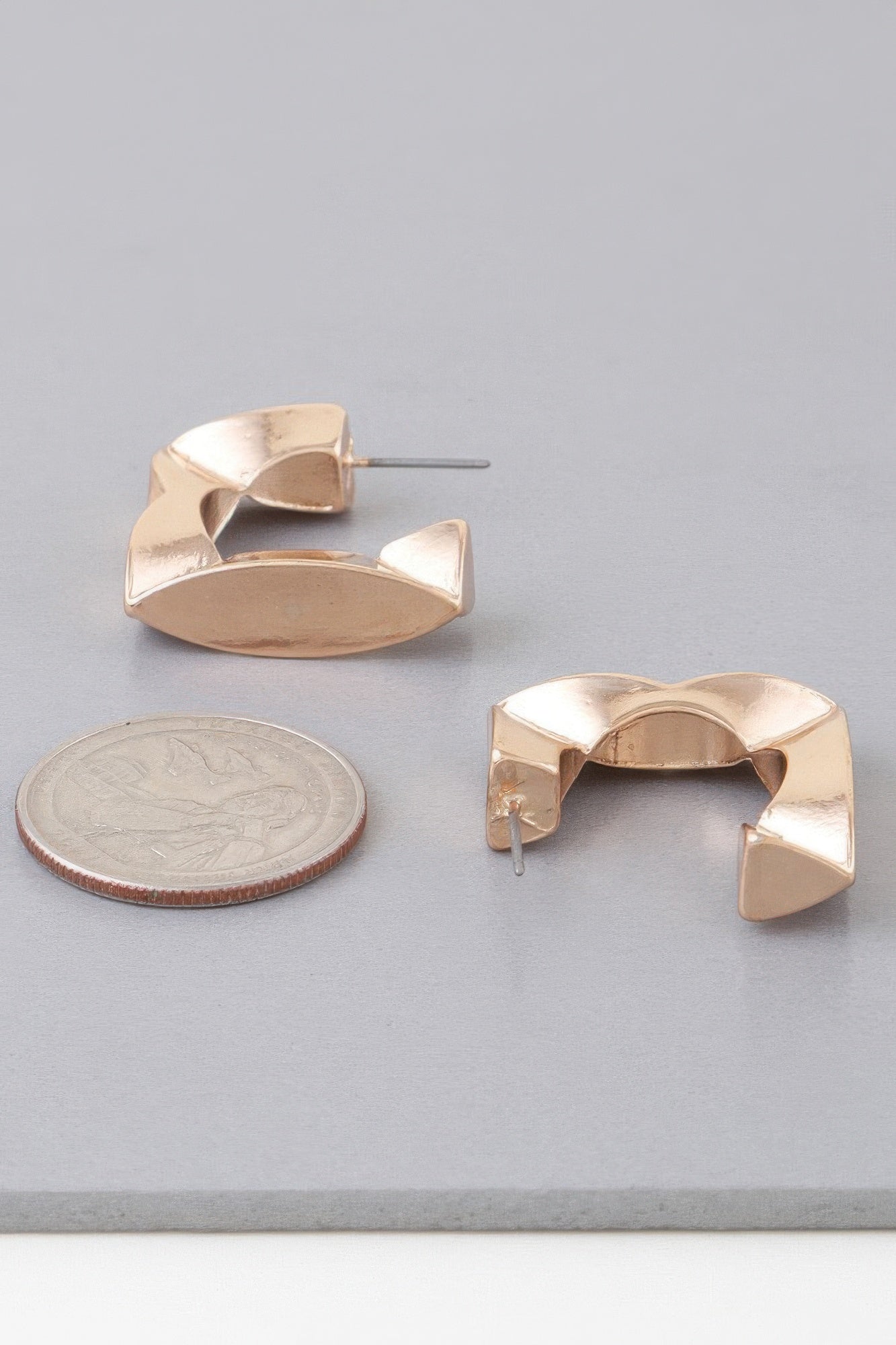Gold geometric cubic hoop earrings, curved open frame with stepped cube facets.
