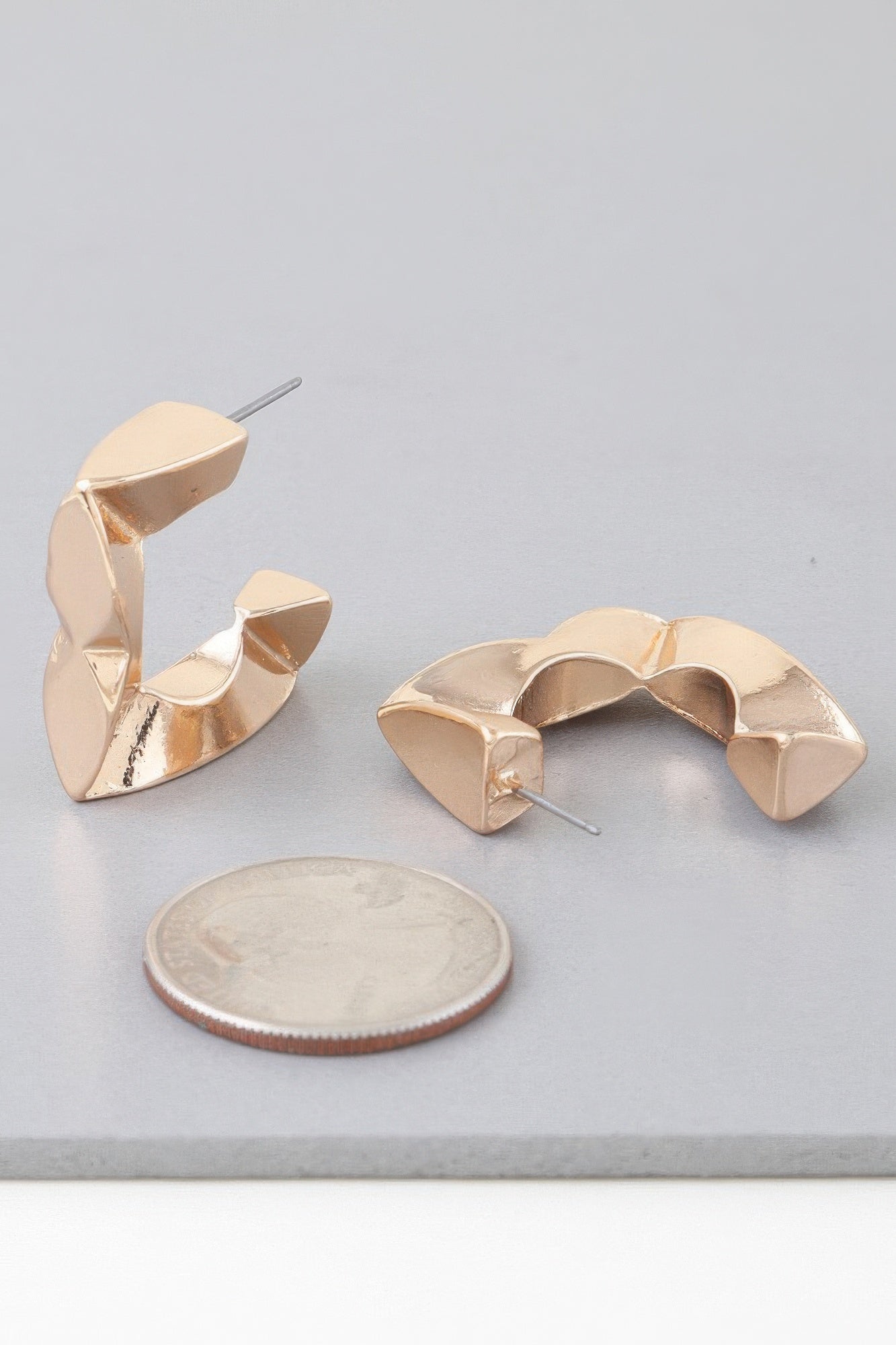 Gold-toned geometric cubic hoop earrings, open arch design with straight stud posts.