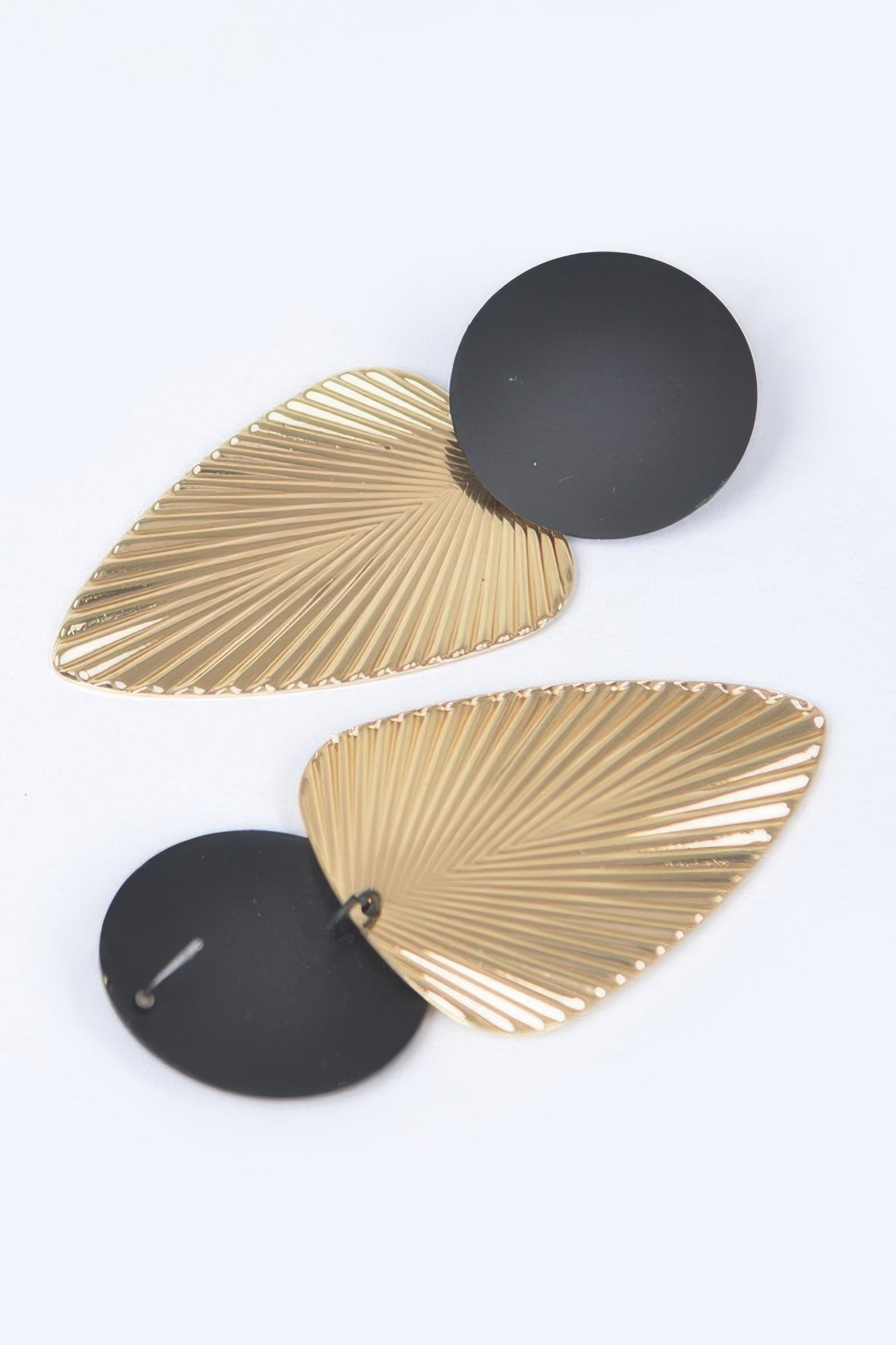 Geometric dangle earrings detail: black round disks with gold teardrop fan shapes