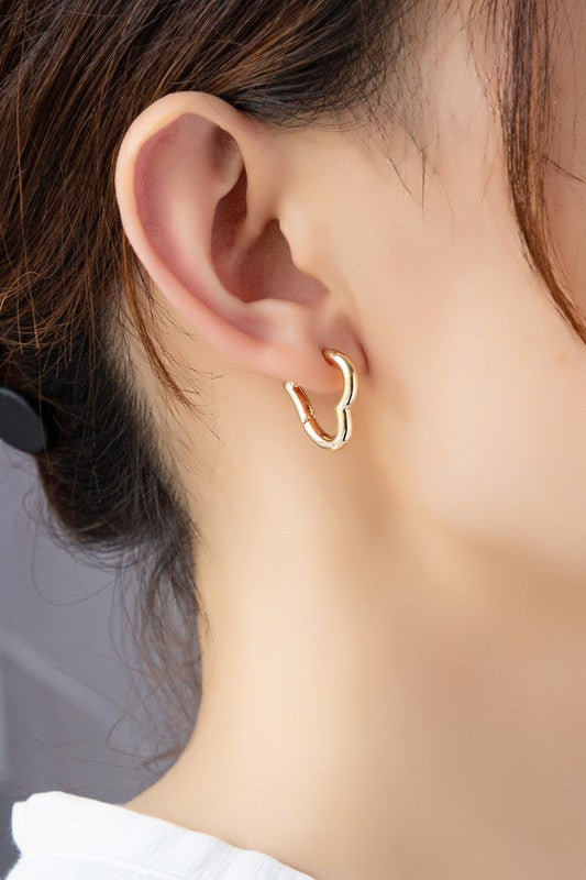 Gold heart hinged huggie hoop earring on ear, curved heart silhouette
