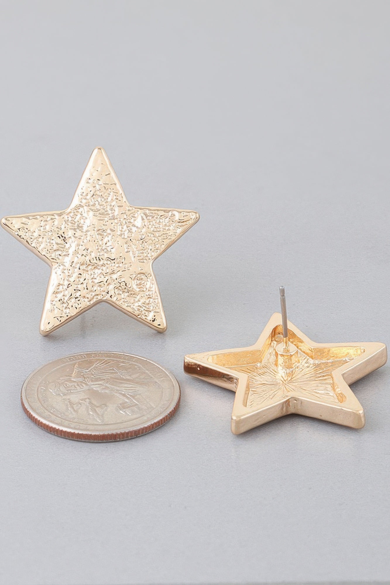 Gold hammered star earrings with needle backs, shown with coin for scale
