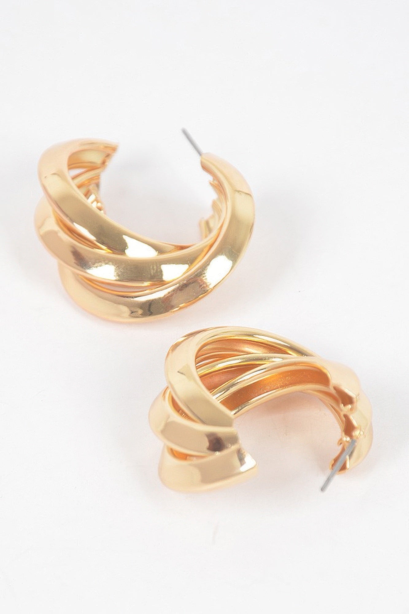 Small gold hoop earrings, layered bands with visible post and clasp
