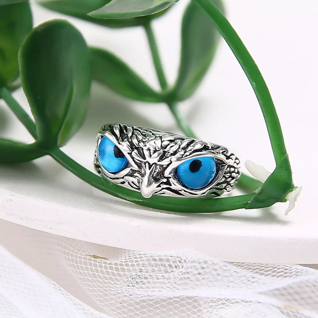 Silver owl eyes ring resting on mesh fabric, three-detailed center with blue eyes