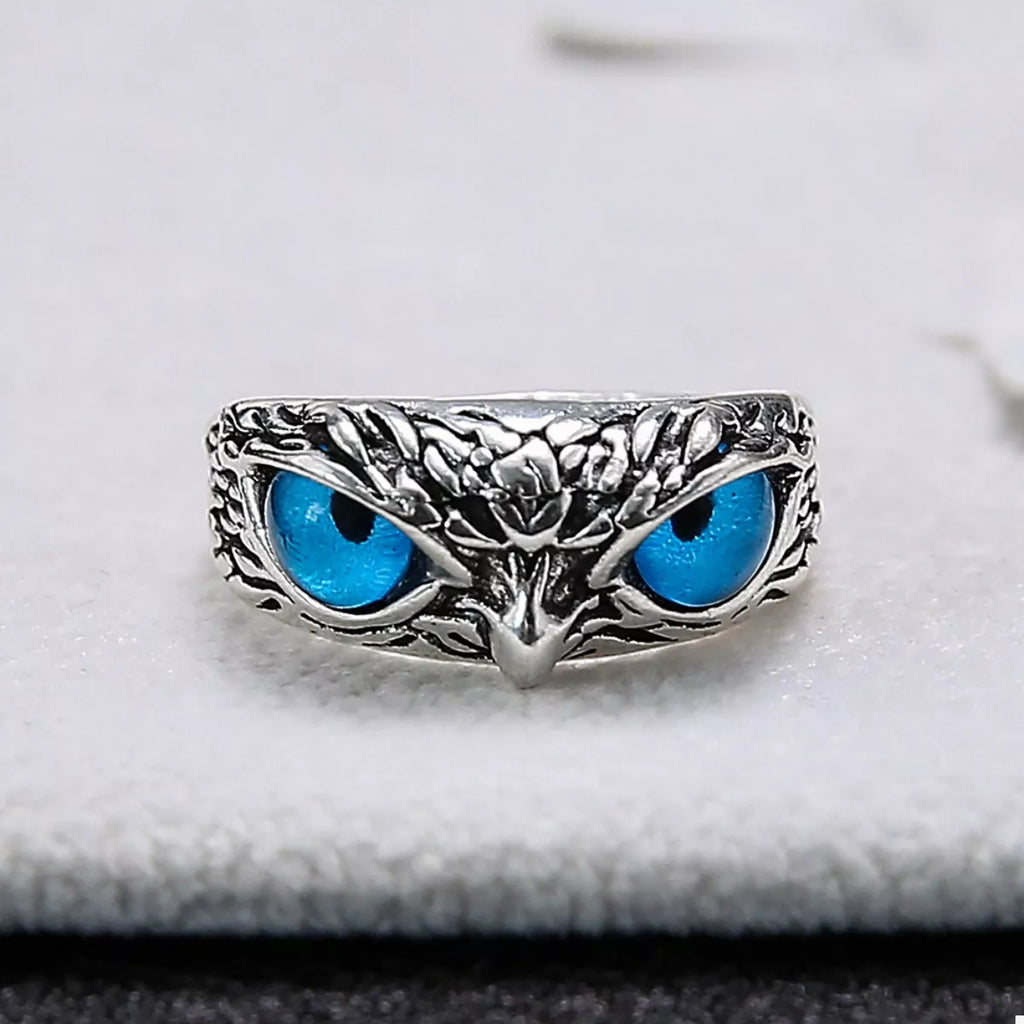 Silver owl eyes ring on gray surface, blue eyes and textured metal filigree