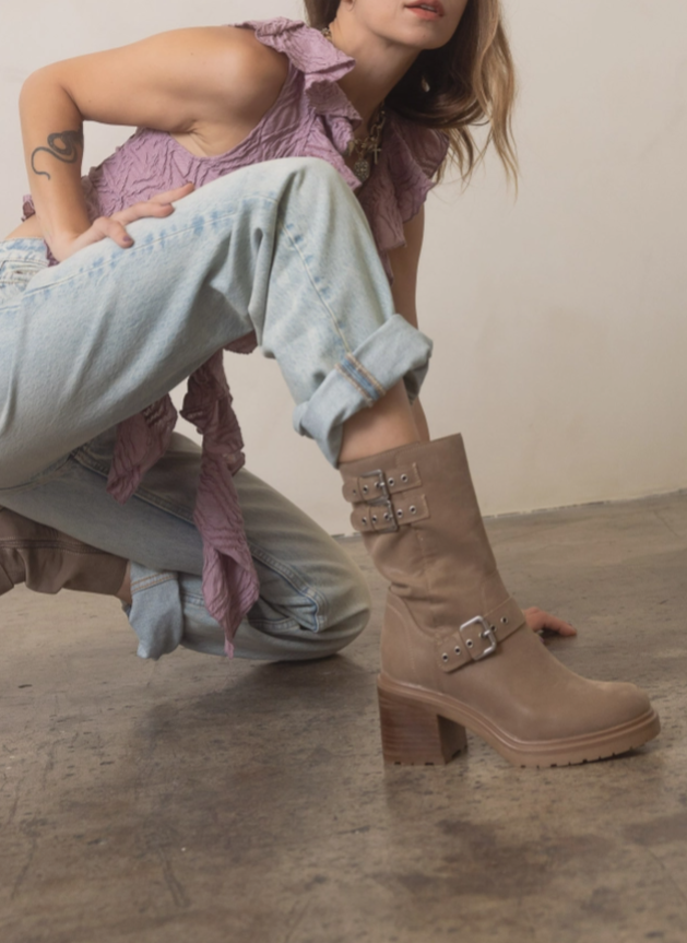 Taupe rider boots worn with straps and silver buckle details, block heel