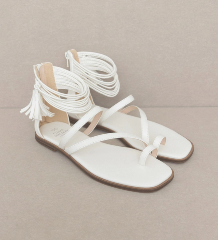 White strappy ankle wrap sandals with fringe tassels and brown flat outsole