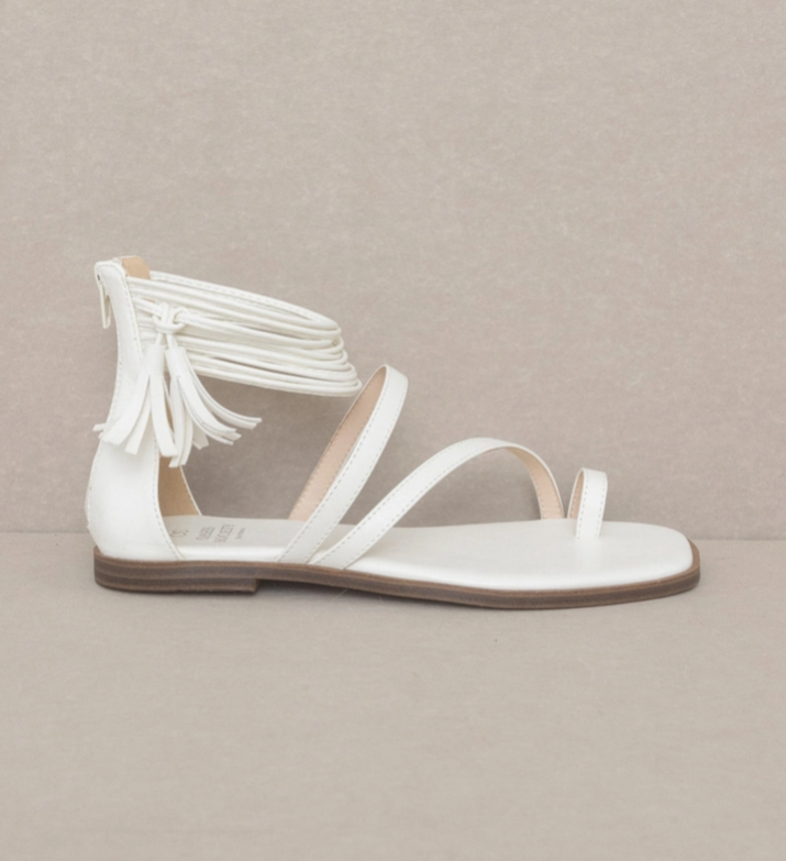 Single white strappy ankle wrap sandal with tassel detail and flat sole