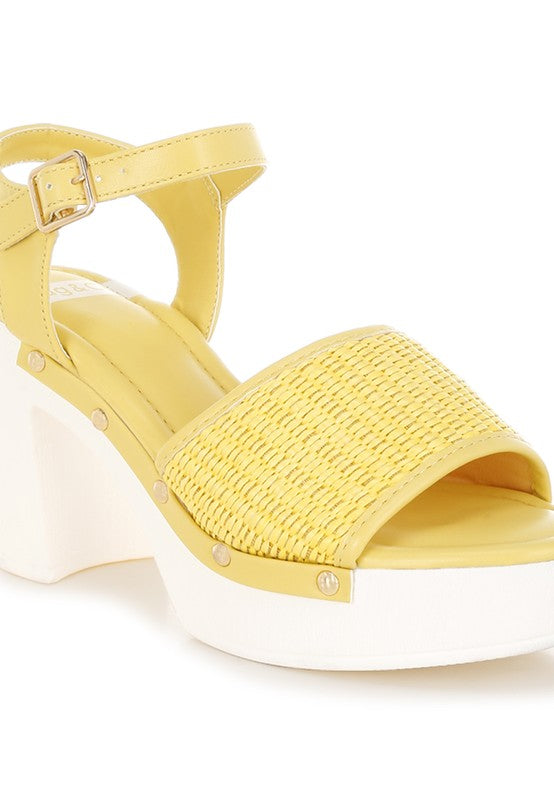 Yellow raffia platform sandals with wide ankle strap, buckle, and chunky white heel