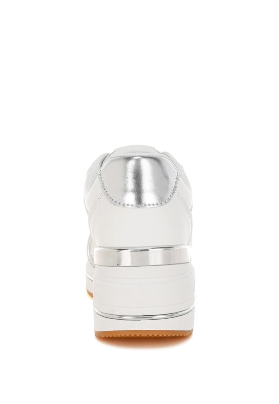 White faux leather sneaker with metallic heel cap and tan gum outsole, rear view