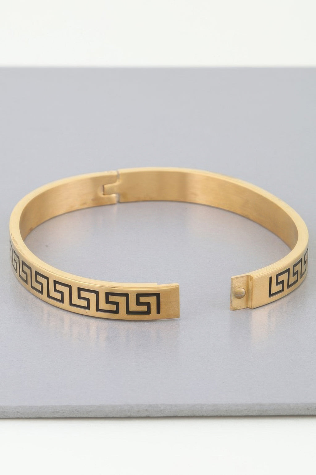 Gold Aztec Maze cuff with hinged clasp and dark Greek-key motif insets