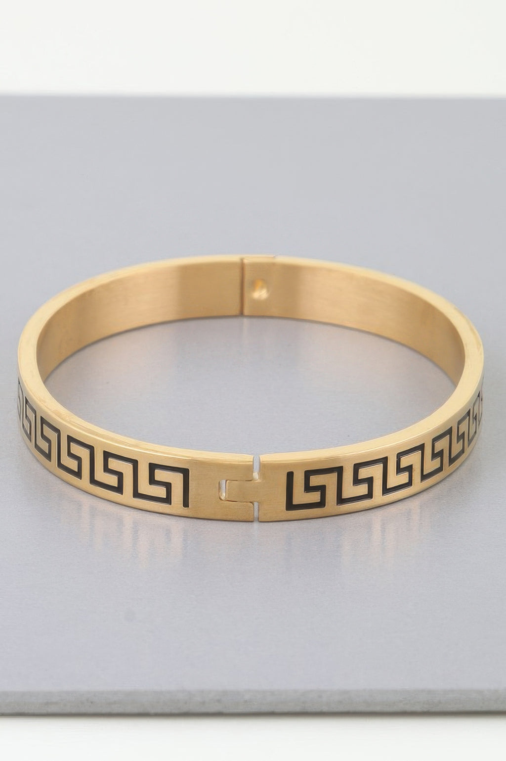 Gold cuff bracelet with center clasp and continuous Greek-key/maze design