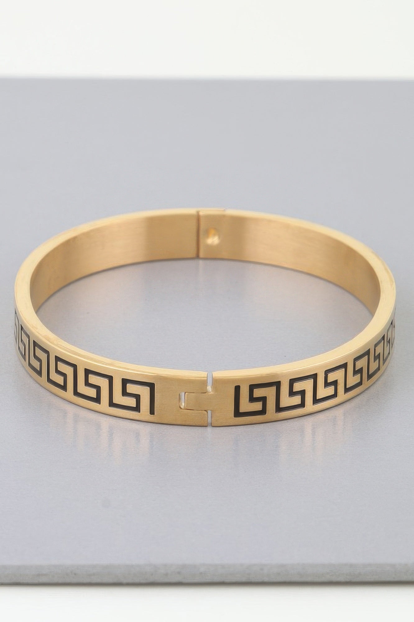 Gold cuff bracelet with center clasp and continuous Greek-key/maze design