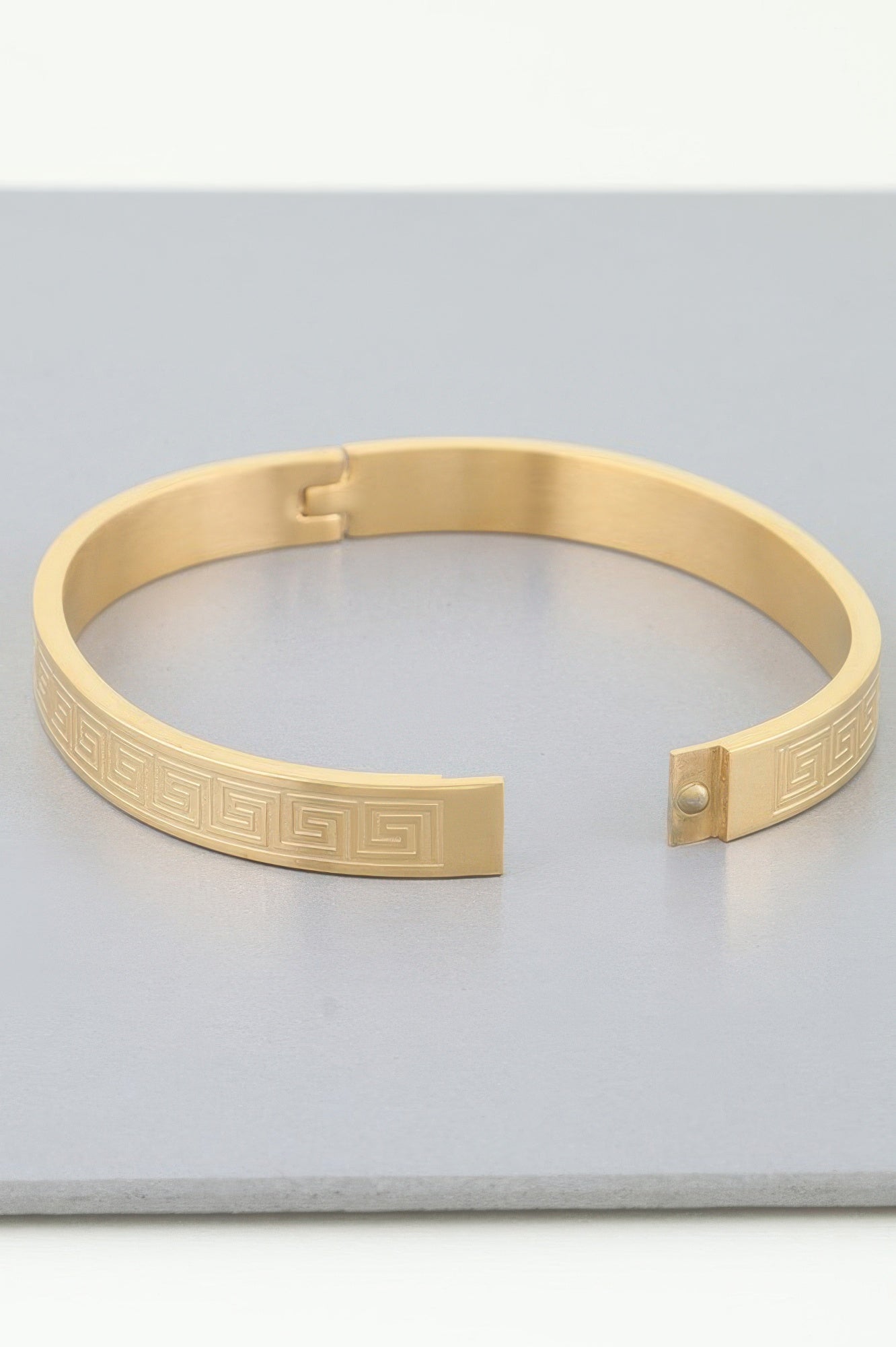 Goldfarbenes Azteken-Maze Armband mit eingravierter Verzierung und Druckverschluss-Detail