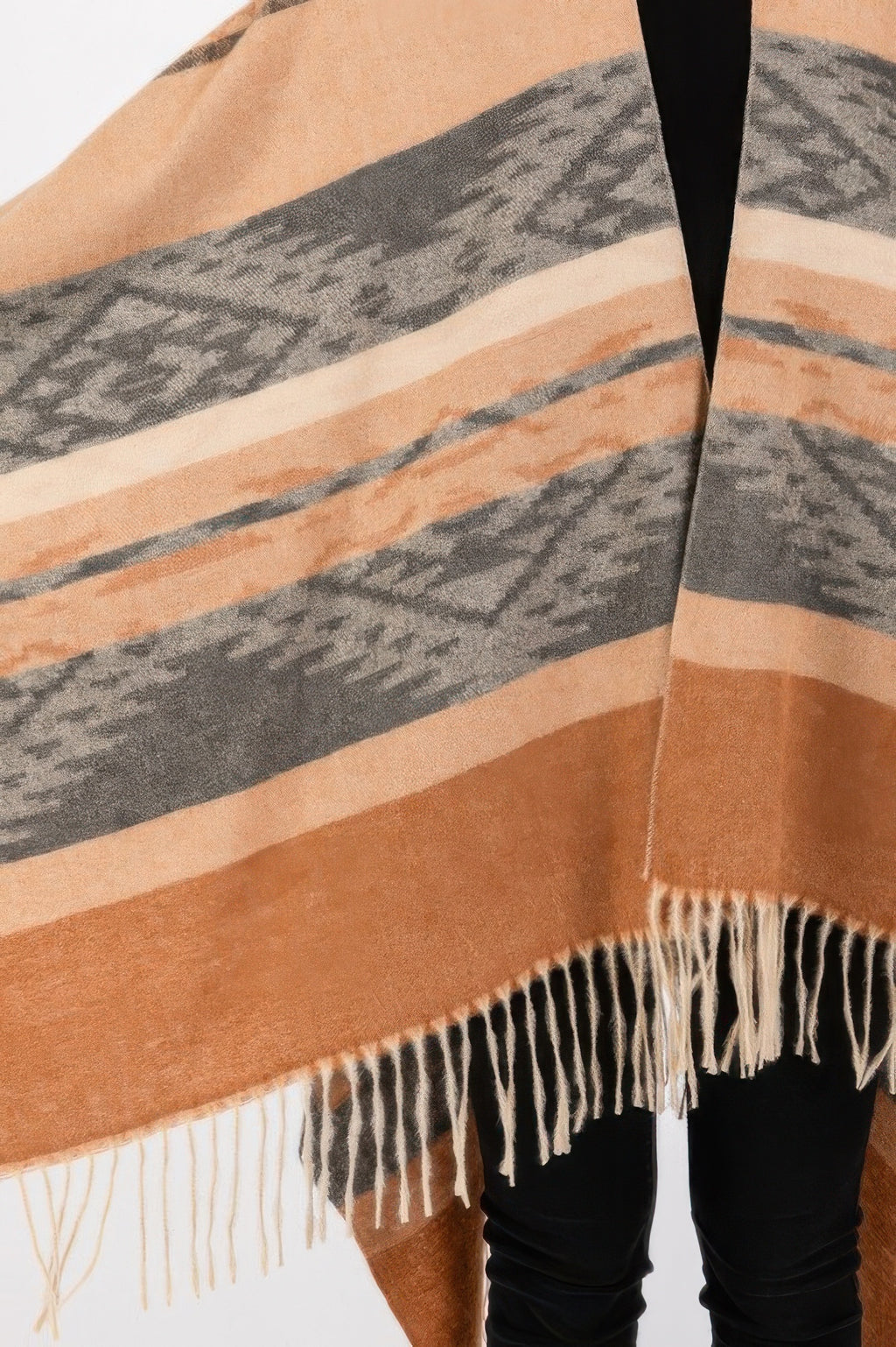 Close-up of taupe aztec-striped ruana with tan, gray, and white fringe trim