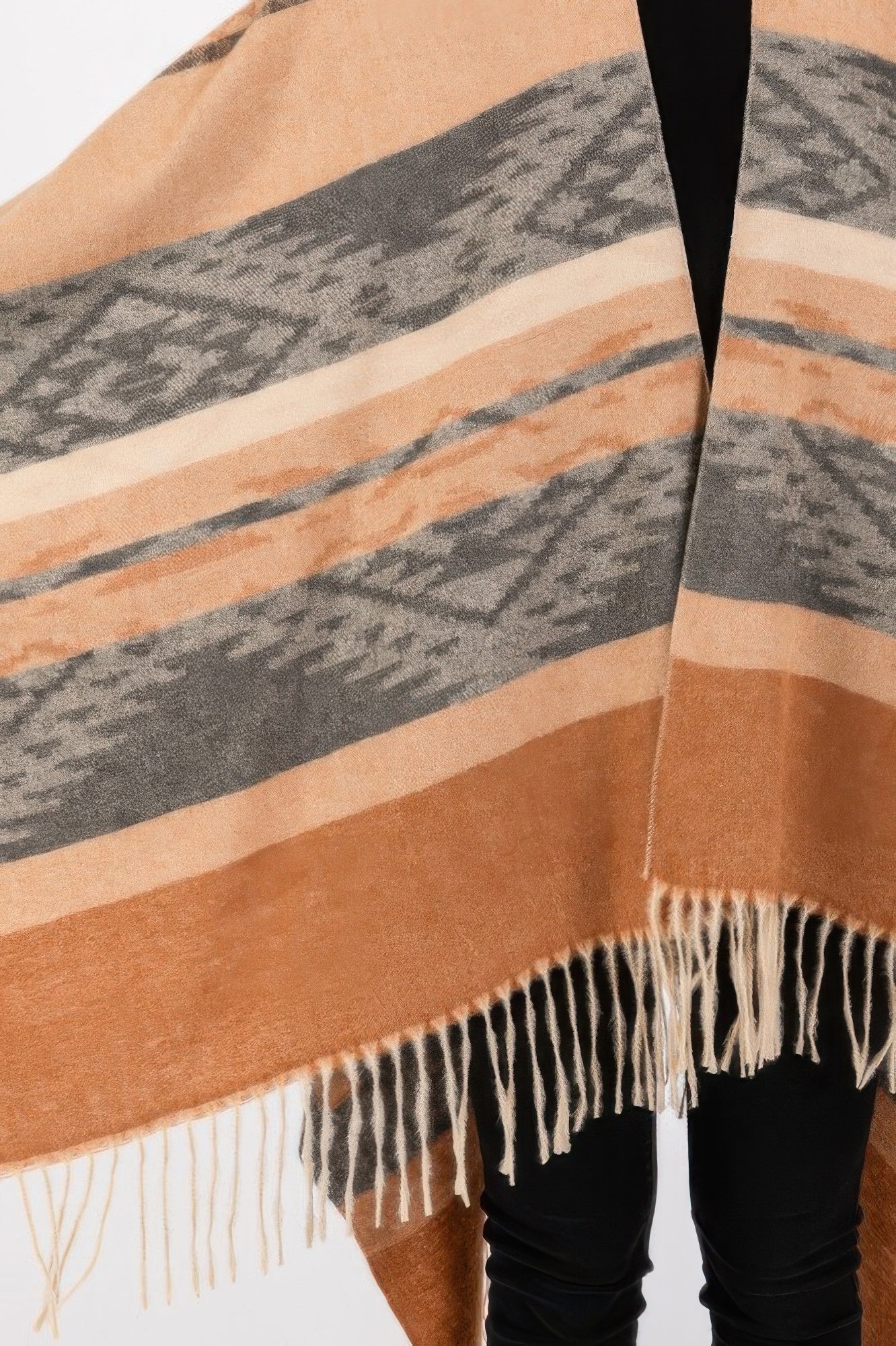Close-up of taupe aztec-striped ruana with tan, gray, and white fringe trim